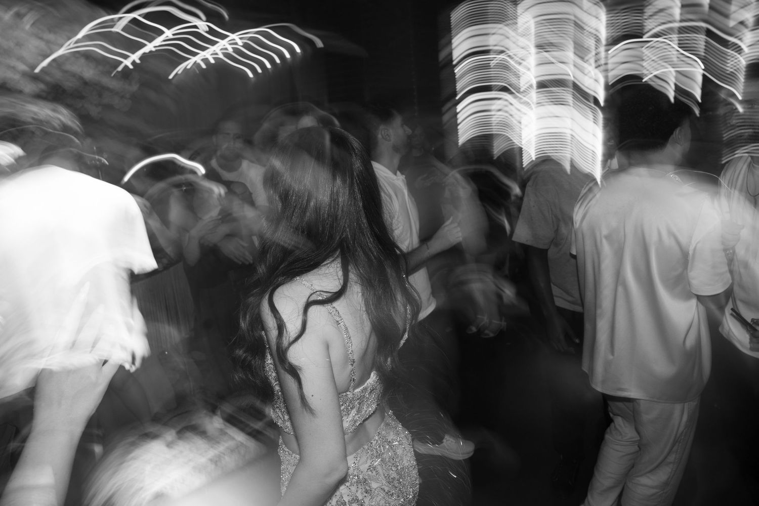 Black and white photo of people dancing at a crowded nightclub with motion blur and light streaks.