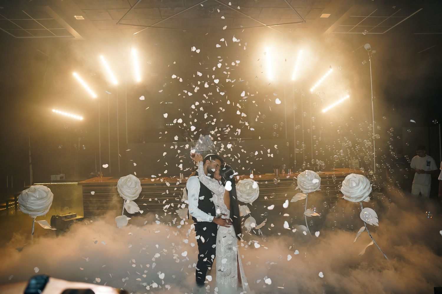 Dramatic wide shot of a wedding reception with confetti falling and ambient lighting.