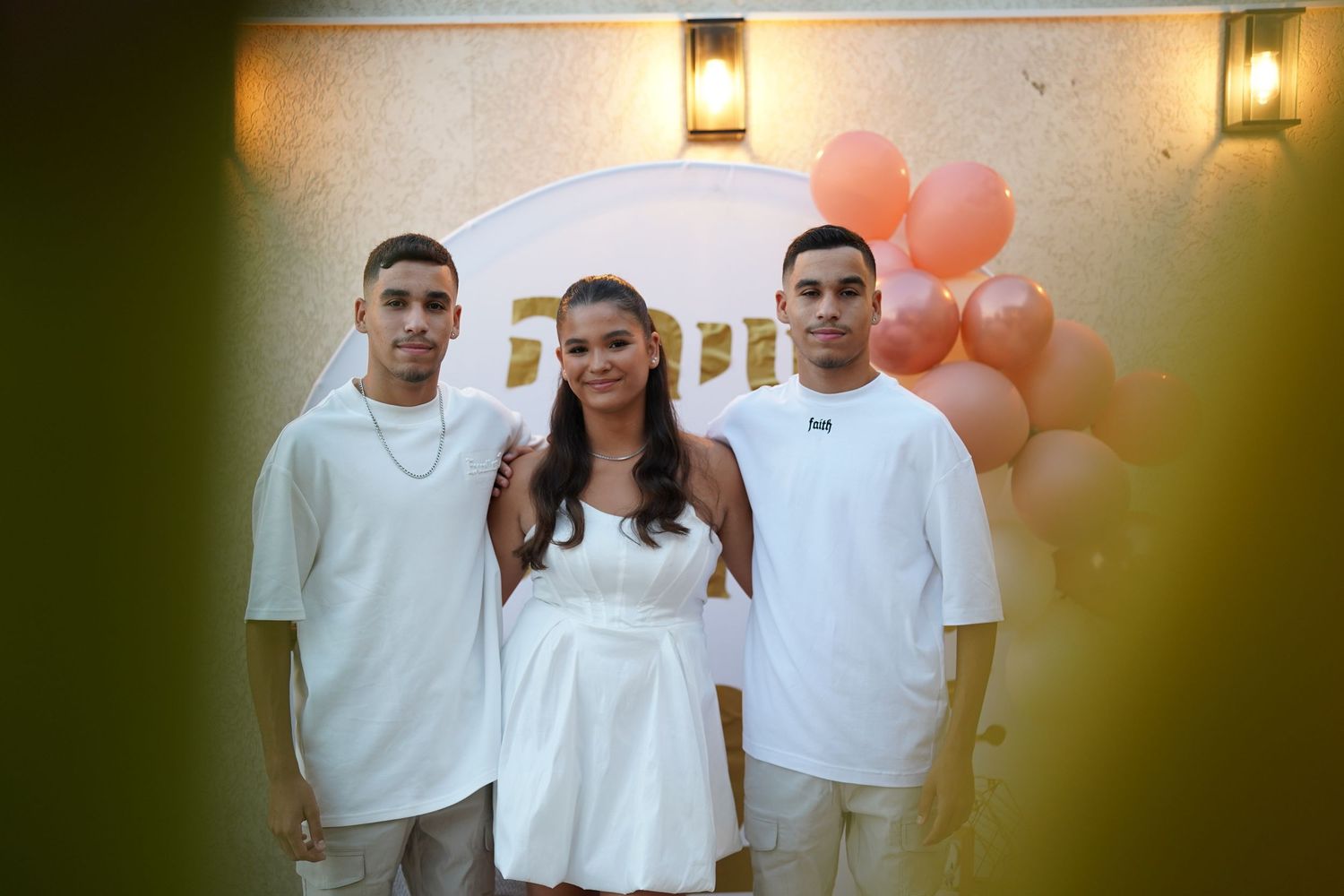 People in white clothing gather for a group photo at an outdoor celebration.
