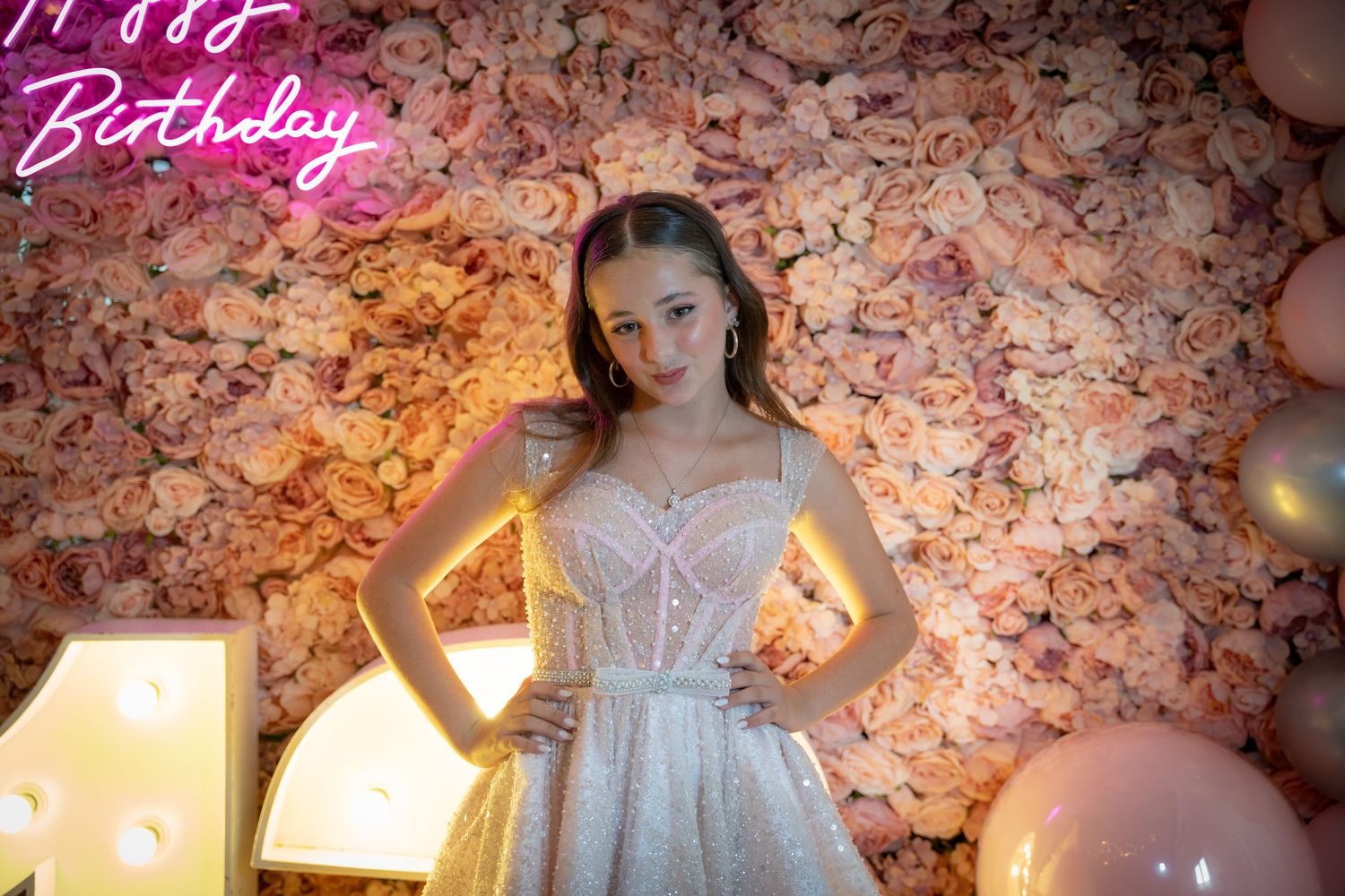 Decorative floral wall with pink neon signage creating a romantic atmosphere.