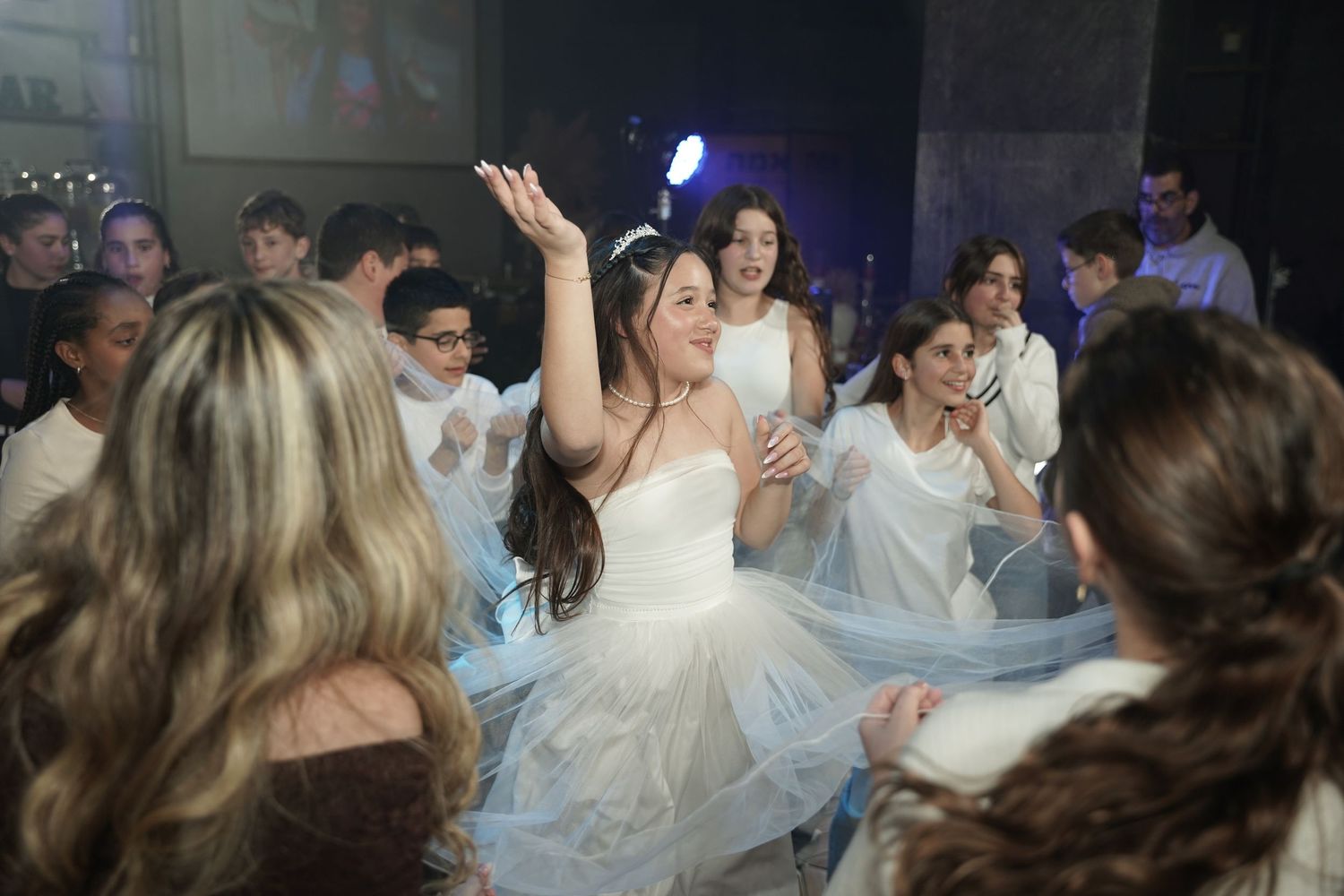 Wedding guests dance and celebrate together on a crowded dance floor at a reception party.