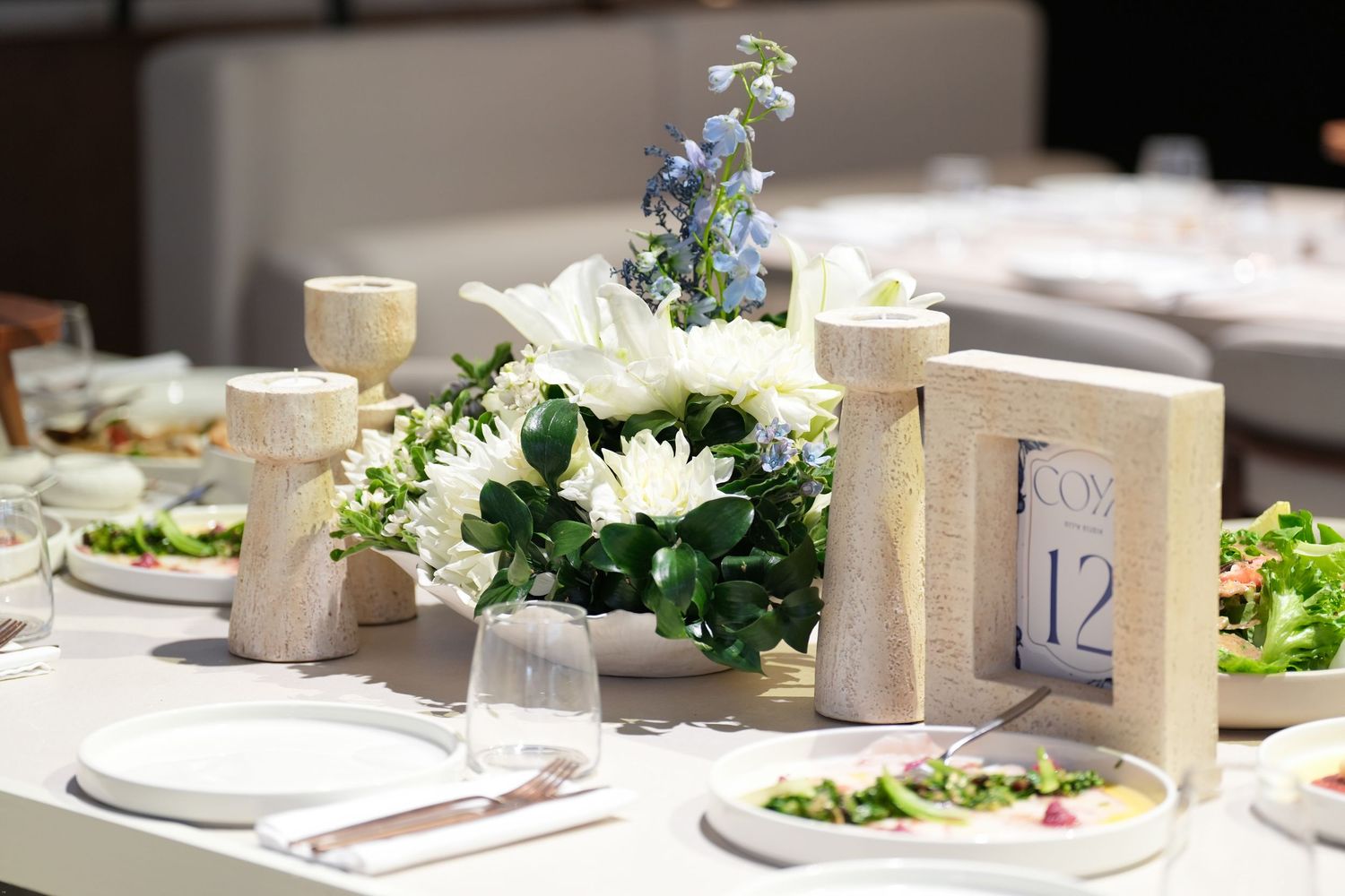 Elegant wedding table settings with white floral centerpieces and numbered table markers create a sophisticated atmosphere.