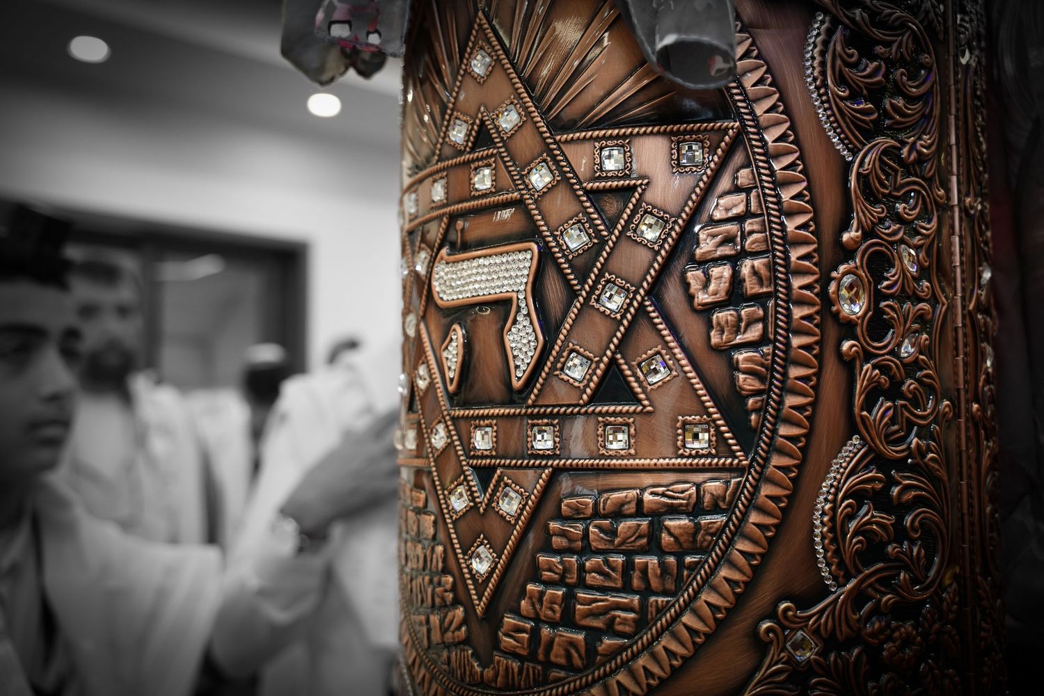 Ornate brown leather Torah case with intricate geometric patterns and decorative metalwork.