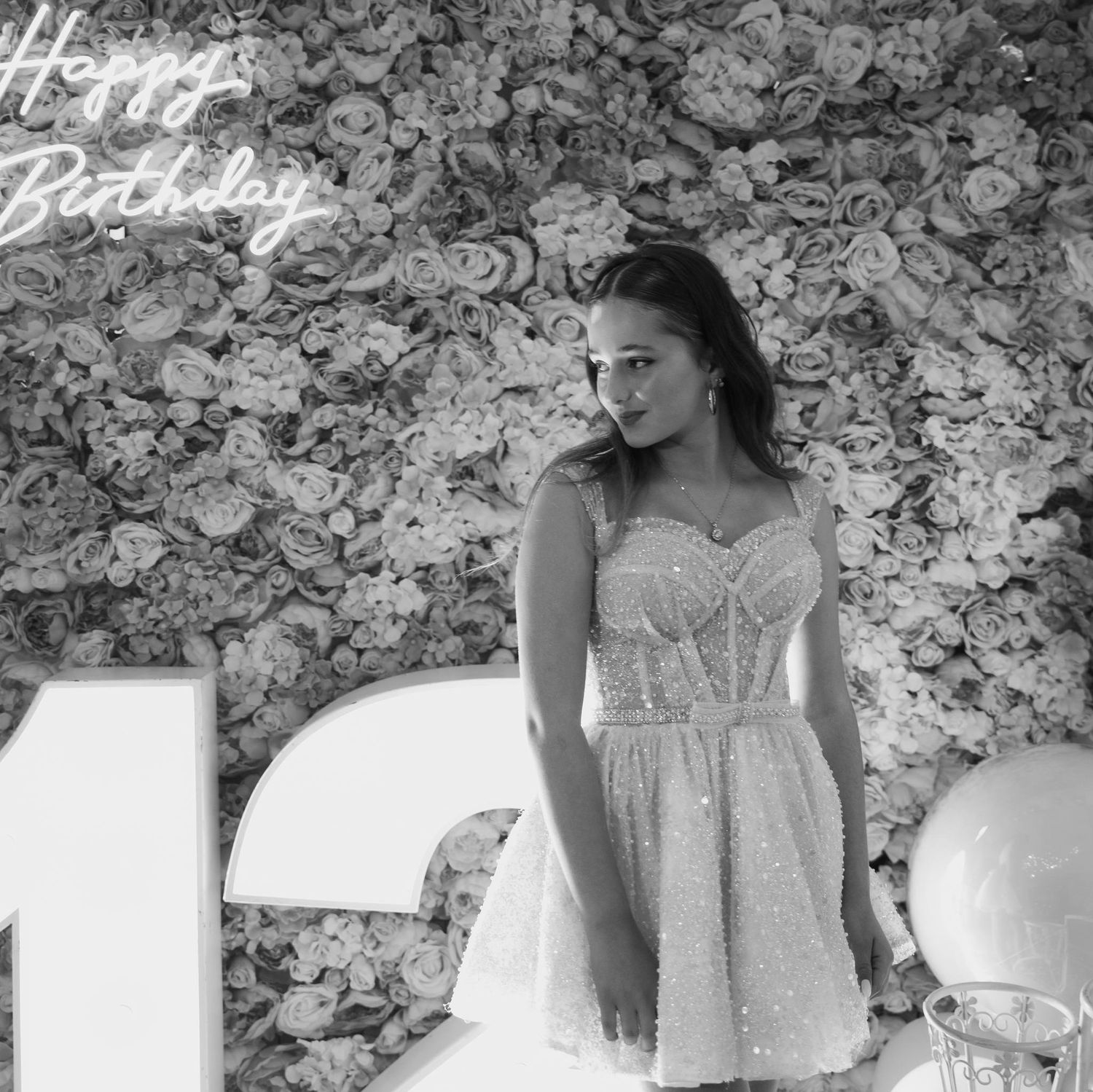 Elegant white wedding dress against a floral backdrop with romantic lighting and decor.
