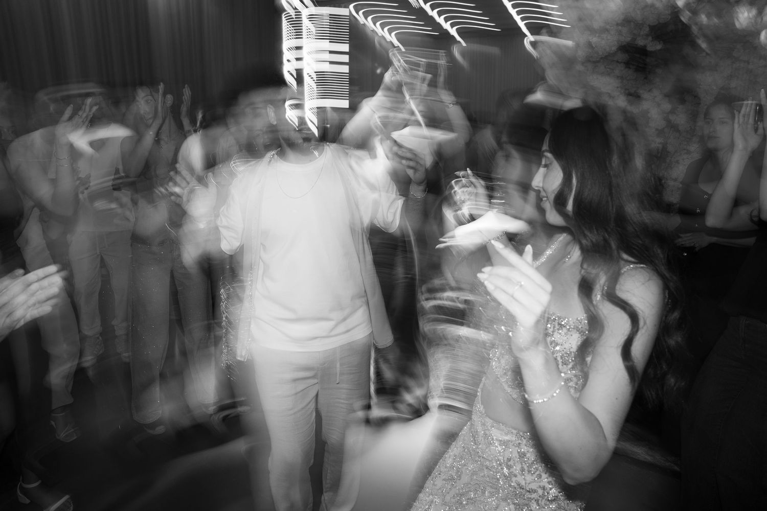 Black and white photo of guests dancing at a lively wedding reception party.
