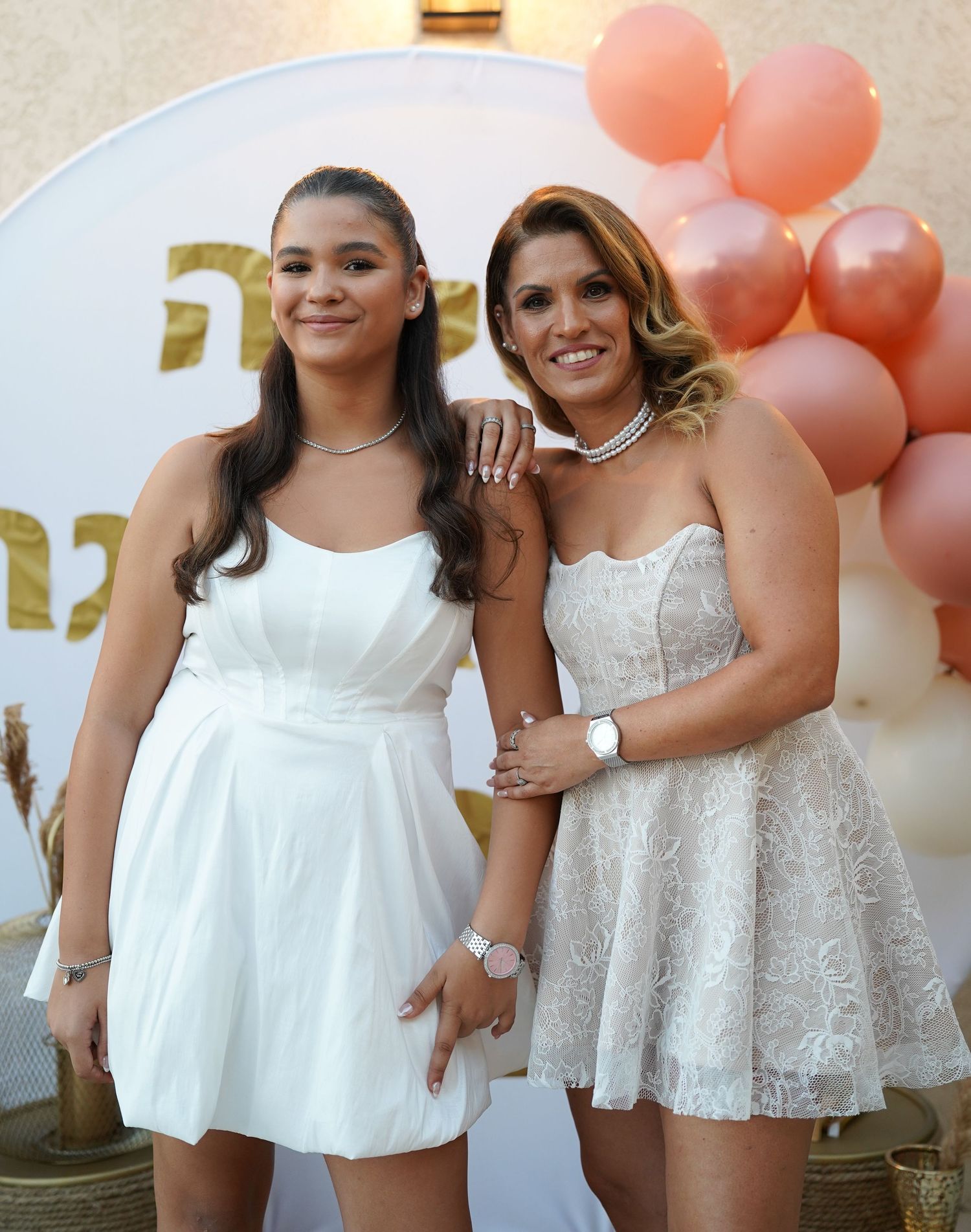 Friends pose together at a celebration wearing coordinating white and lace outfits.