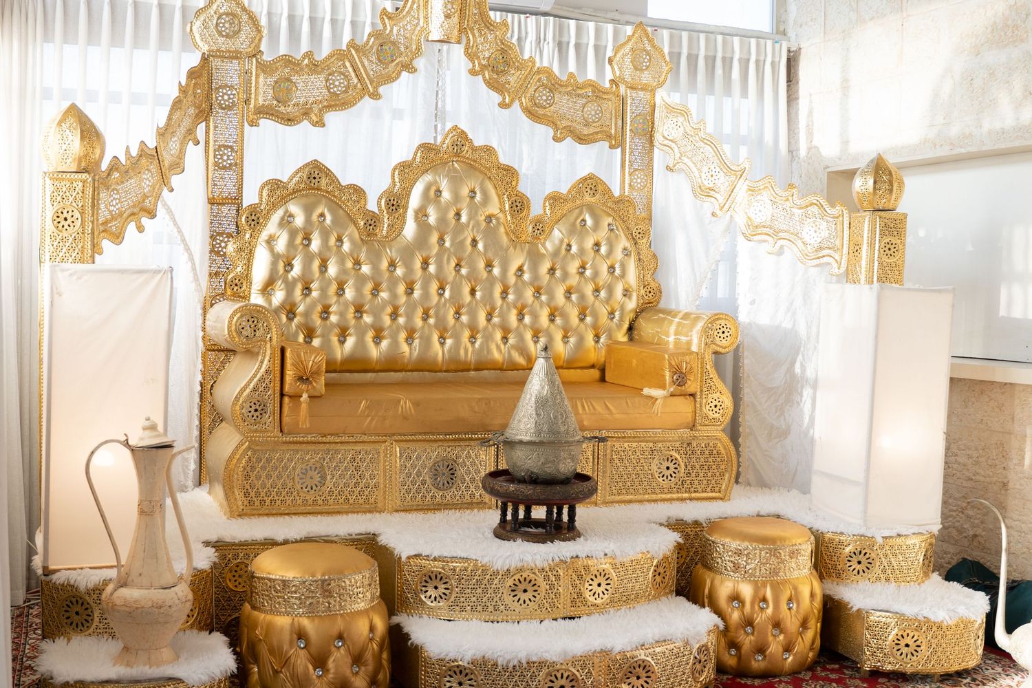 Panoramic view of ornate gold throne seating against white backdrop with decorative details.