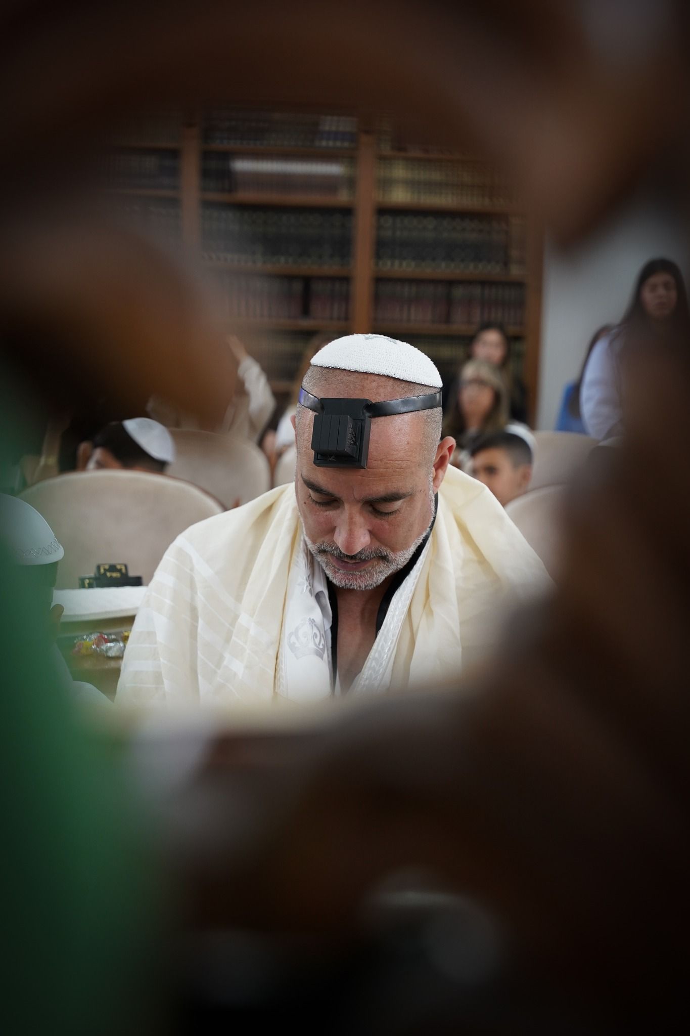 Jewish prayer service with traditional tefillin and prayer shawls.
