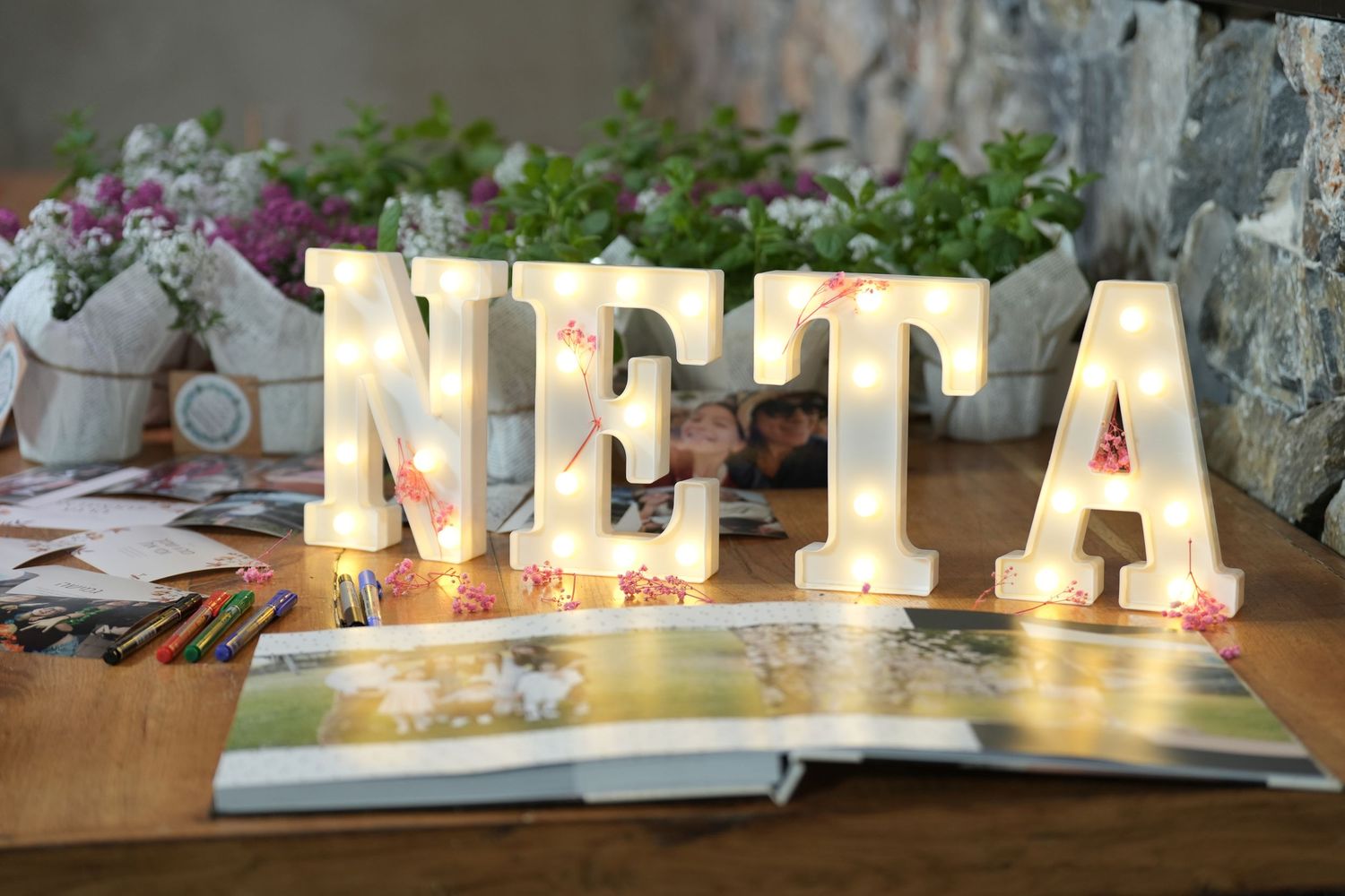 Illuminated white marquee letters spelling 'NIFTA' displayed on a table with decorative elements in the background.