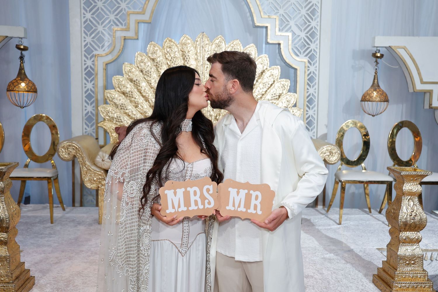 Elegant wedding venue interior with ornate gold and white decor featuring romantic lighting and decorative arches.