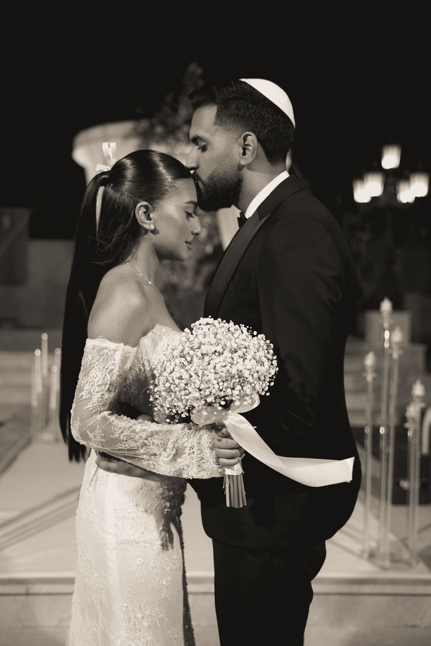 A black and white wedding portrait with traditional Jewish elements and baby's breath bouquet.