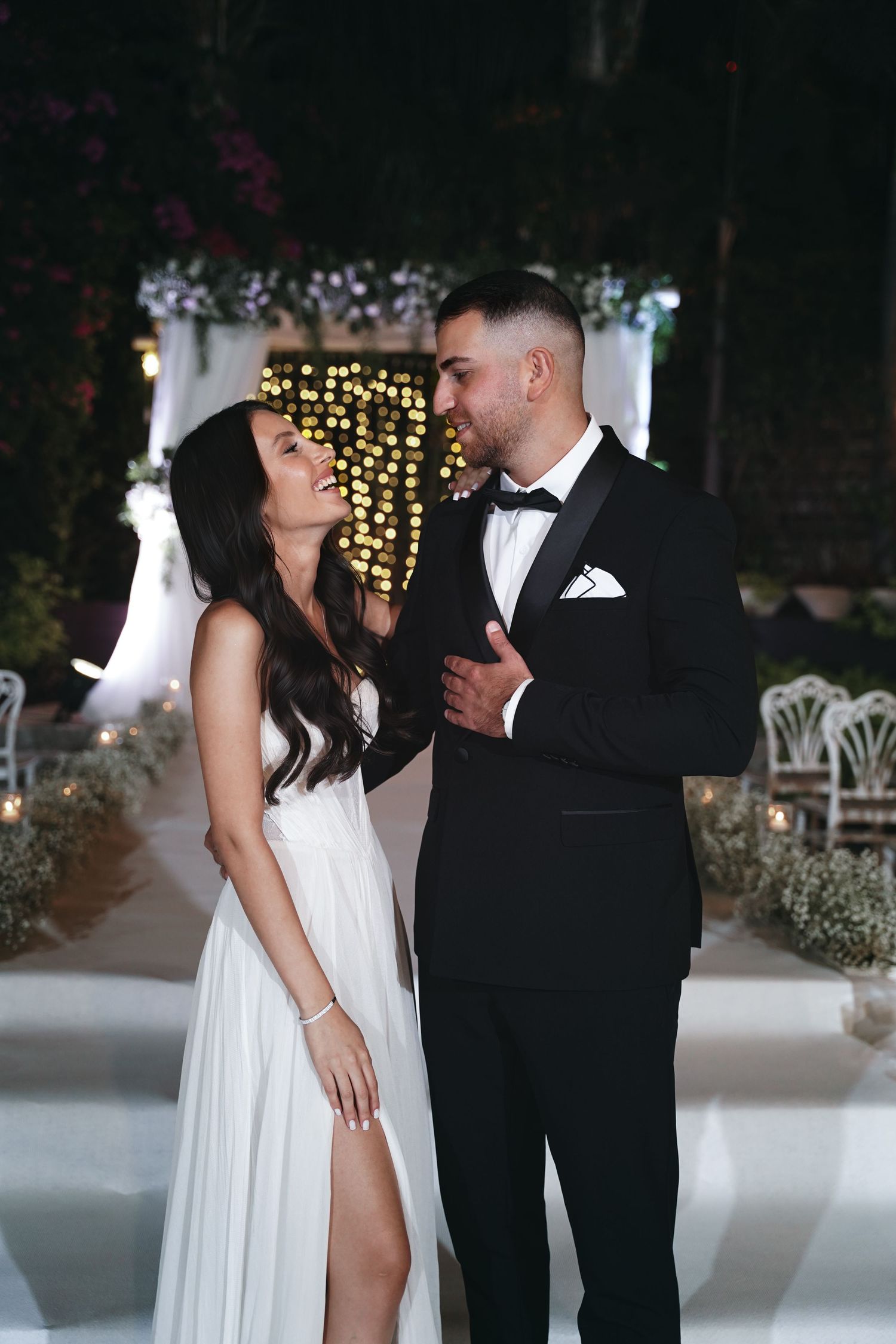 A glamorous evening wedding photo with twinkling lights and elegant attire.