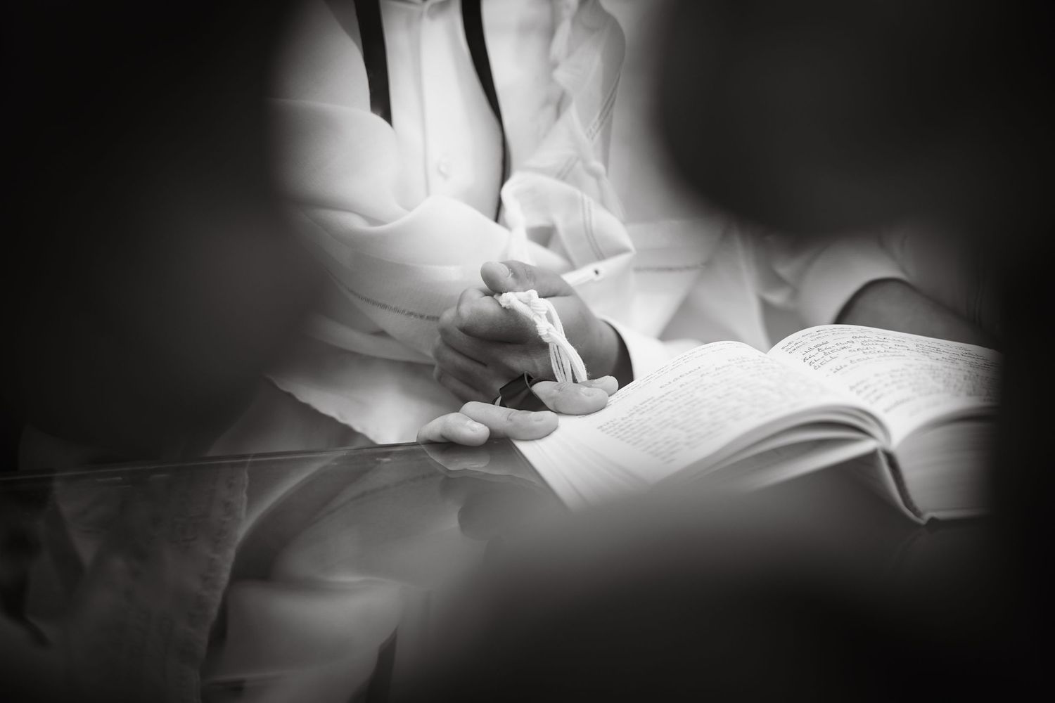 Black and white close-up shot of hands holding open pages of a religious text.
