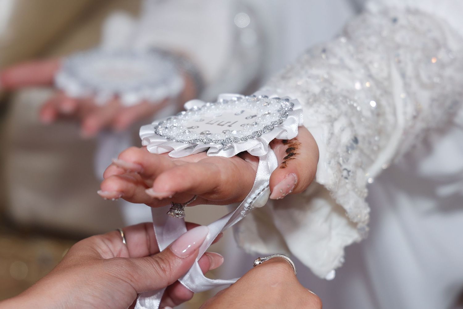 Close-up of hands adjusting delicate white lace on formal attire.
