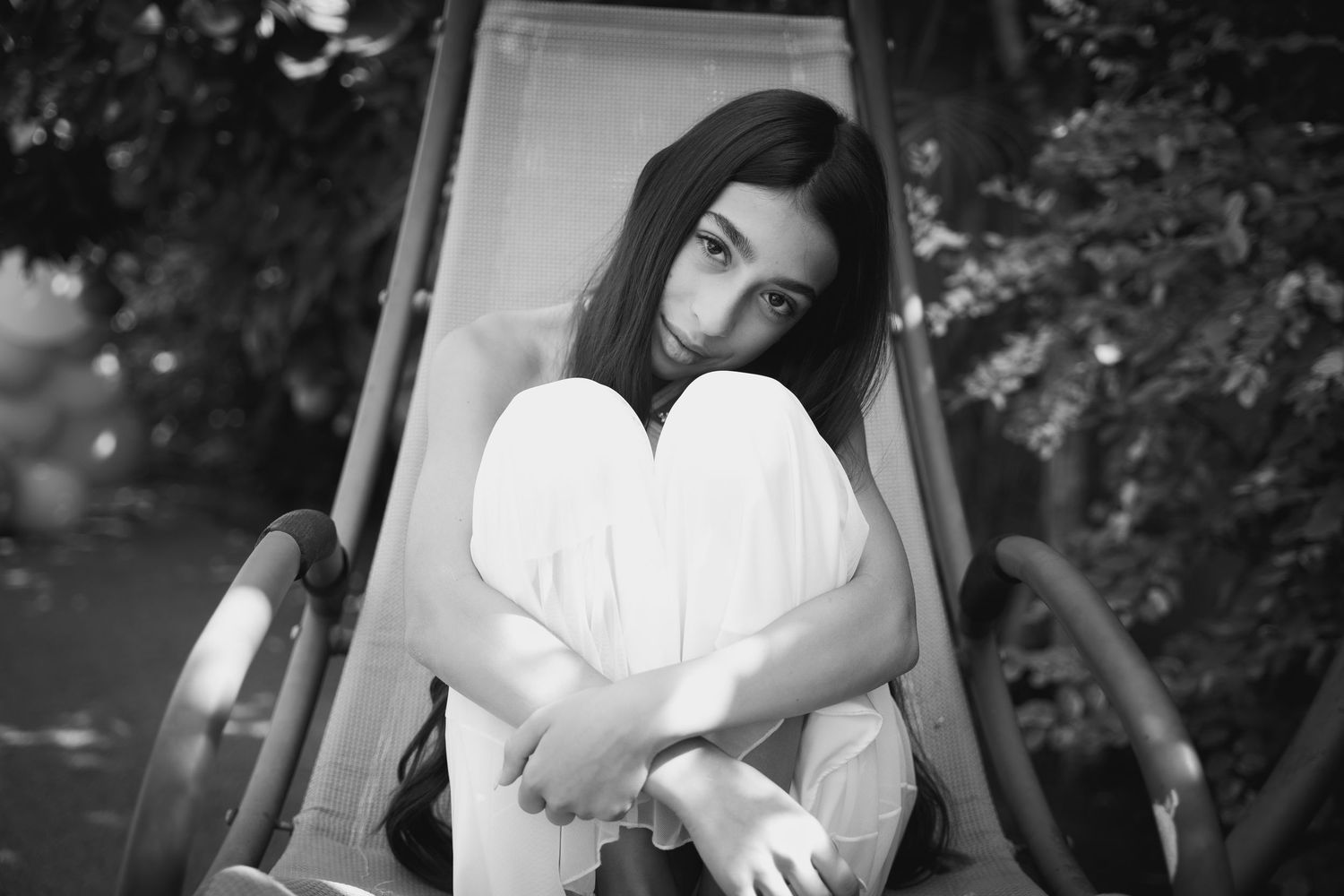 Black and white artistic portrait in an outdoor garden setting.