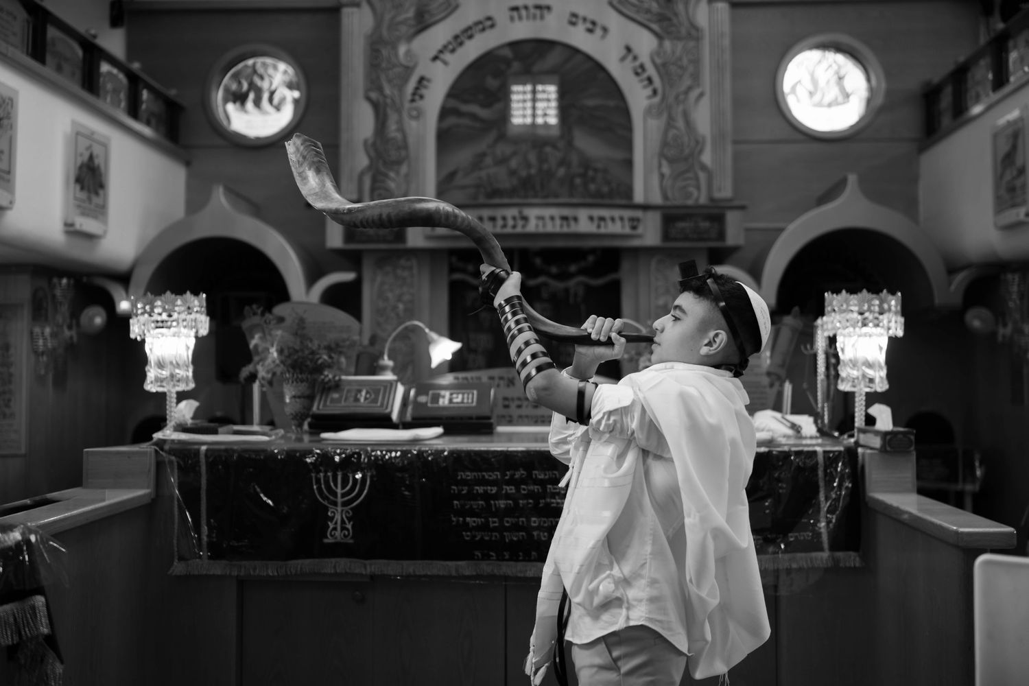 A black and white photo of someone celebrating in a synagogue interior.
