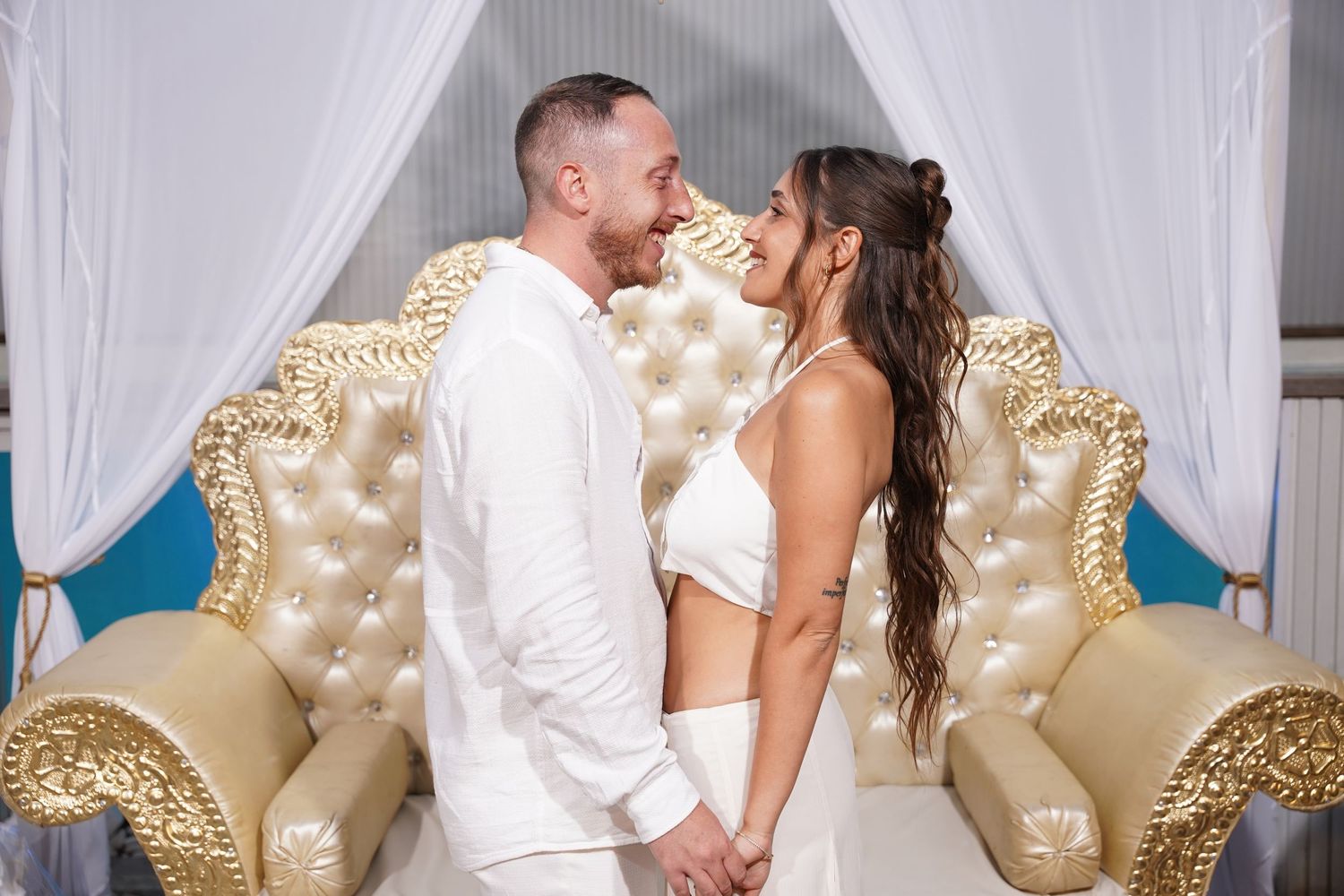 Intimate wedding photos featuring a couple sharing tender moments on an ornate cream sofa.