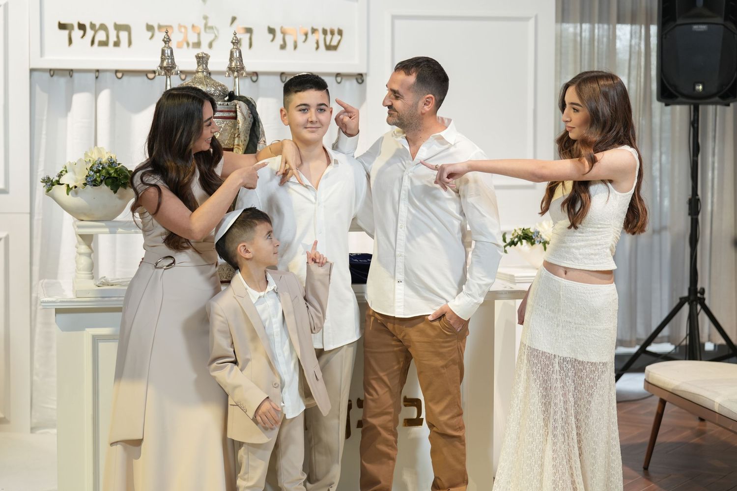 Wedding guests dance and celebrate together at a joyful reception in a bright indoor venue.