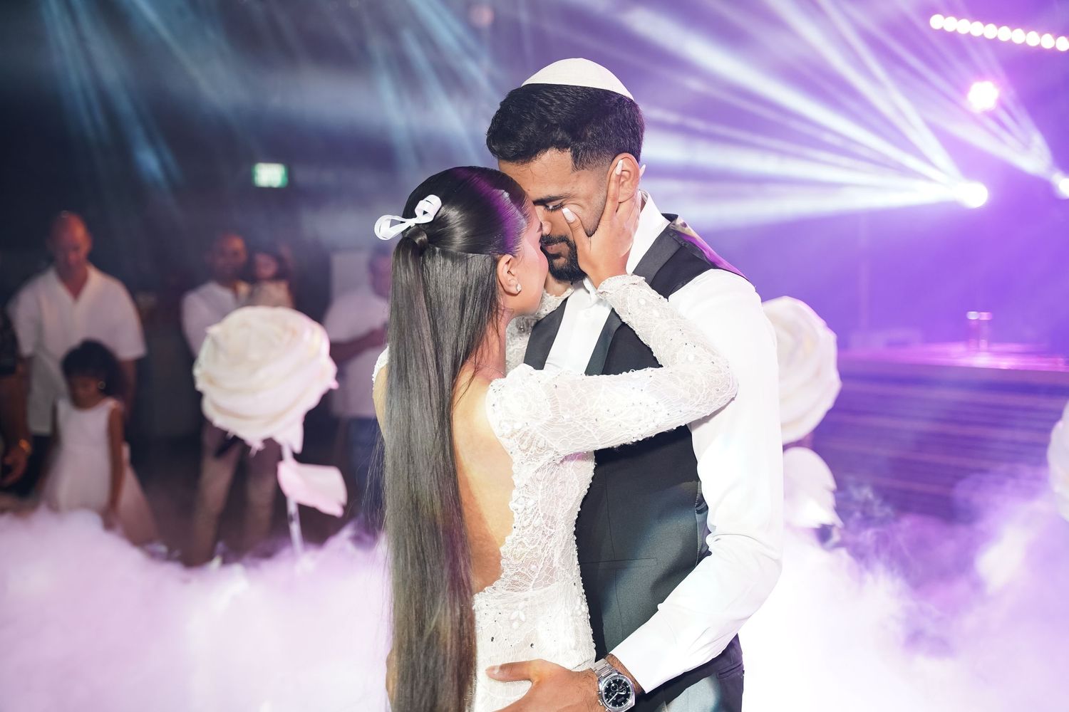 Couple dancing in purple stage lighting with atmospheric effects at their wedding reception.
