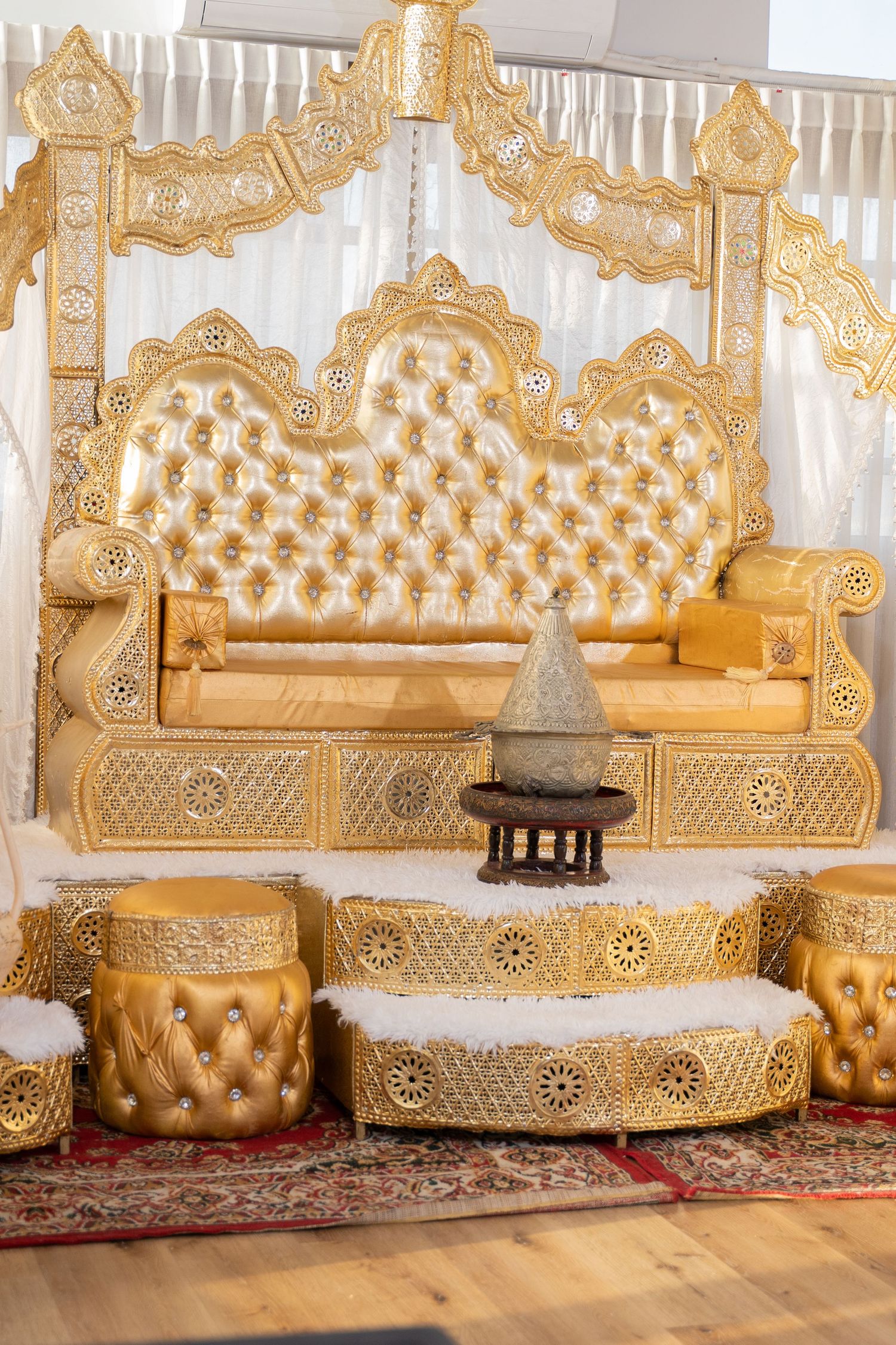 Luxurious gold tufted seating arrangement with ornate carved details against white backdrop.
