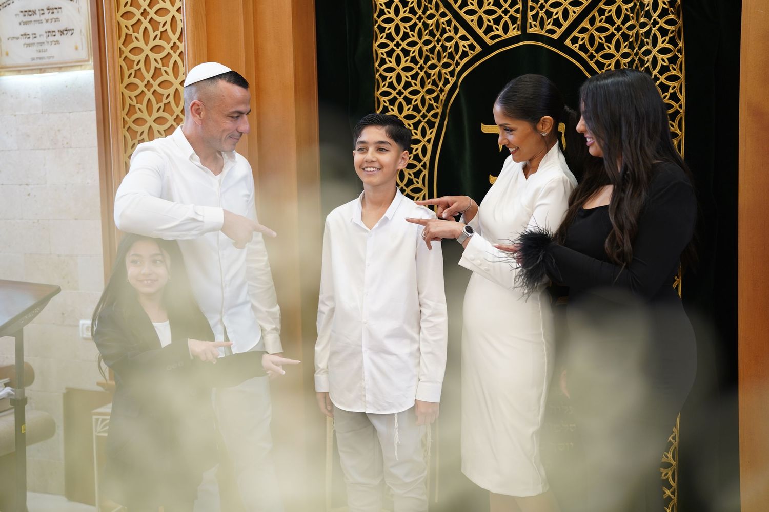 Religious ceremony participants in white attire standing before decorative screen.