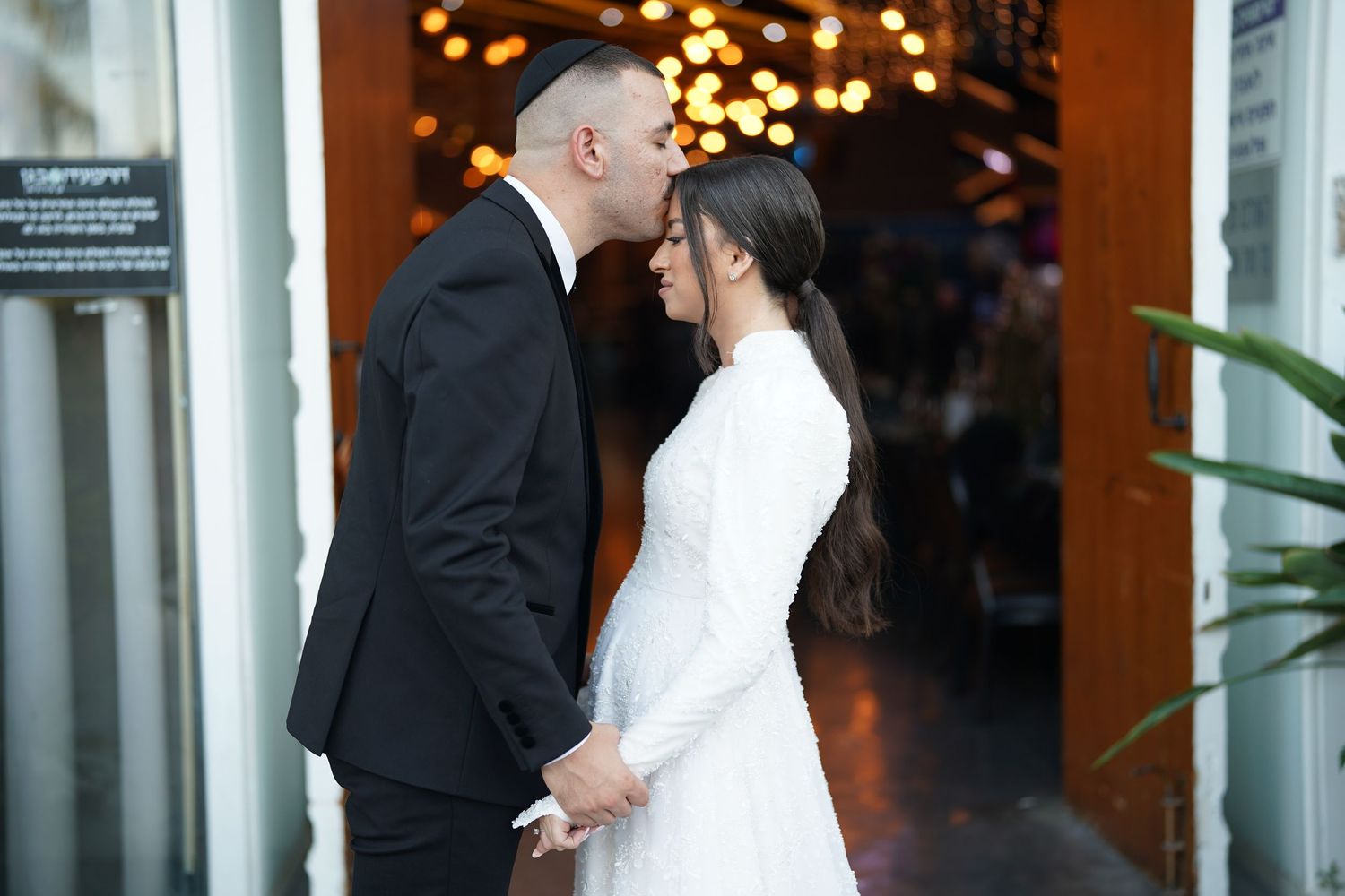 An intimate moment between a couple in formal attire at their wedding venue entrance.