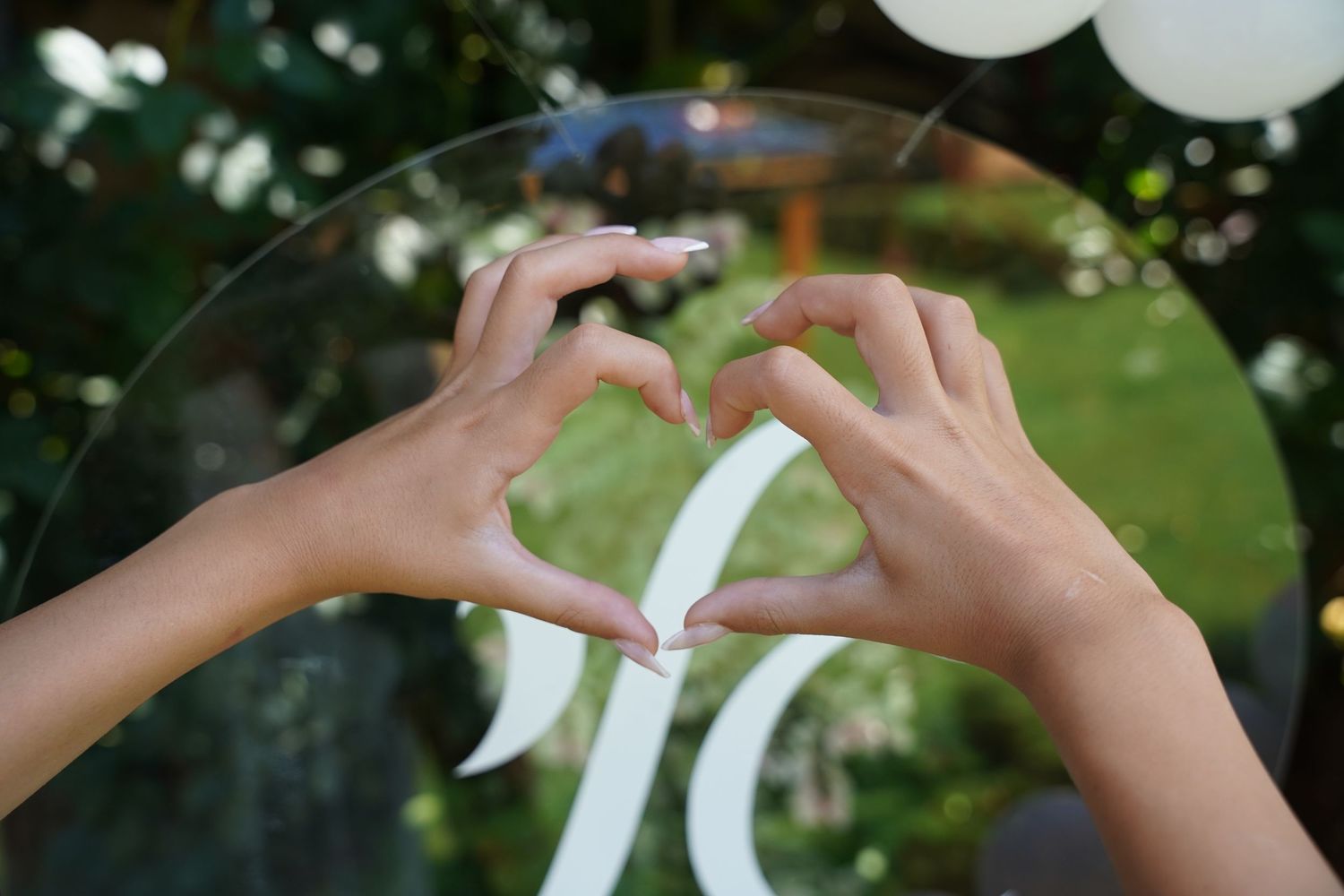Close-up of hands arranging white balloon decorations outdoors.