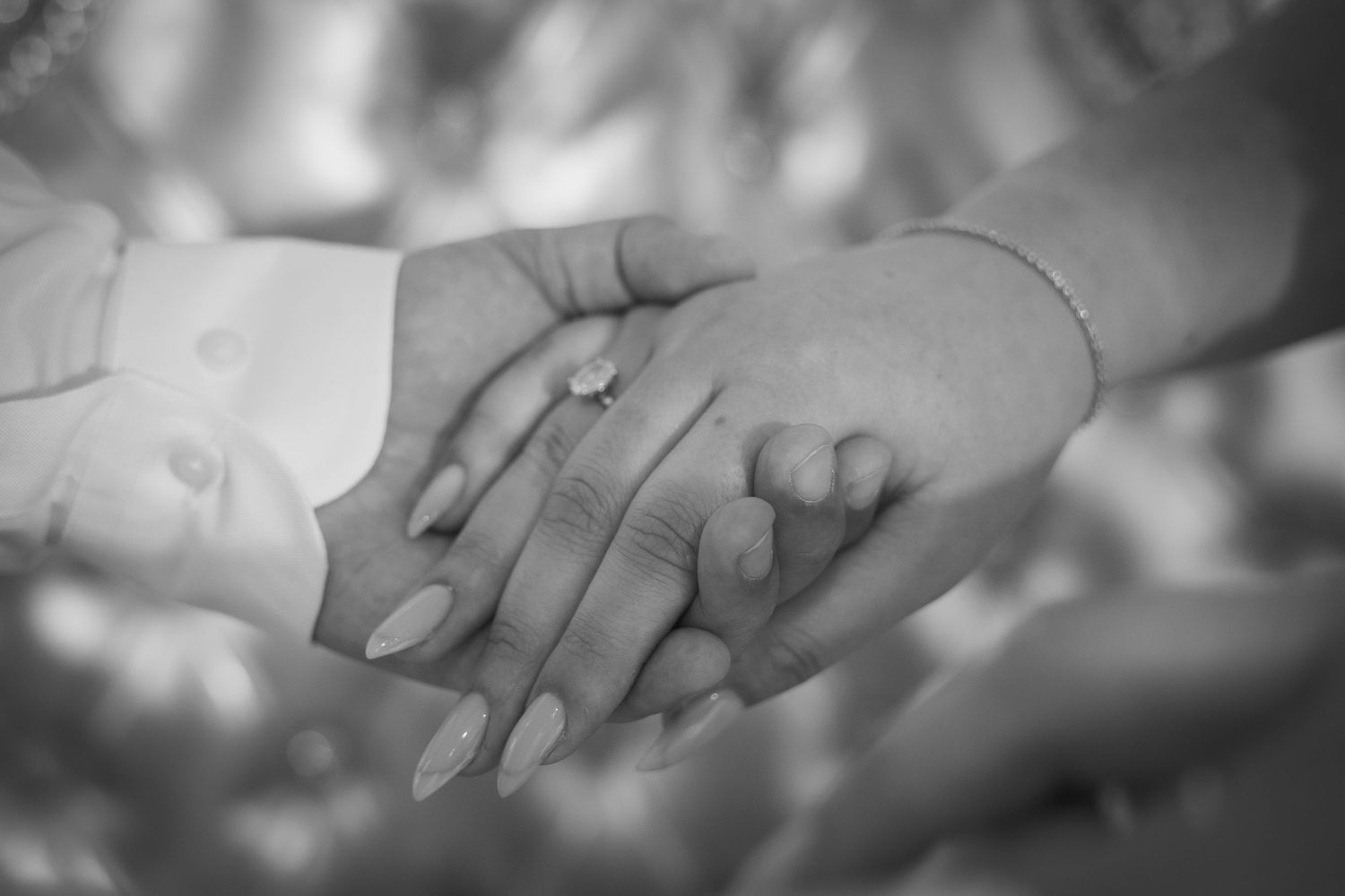 Black and white detail shot of hands and rings in romantic pose.