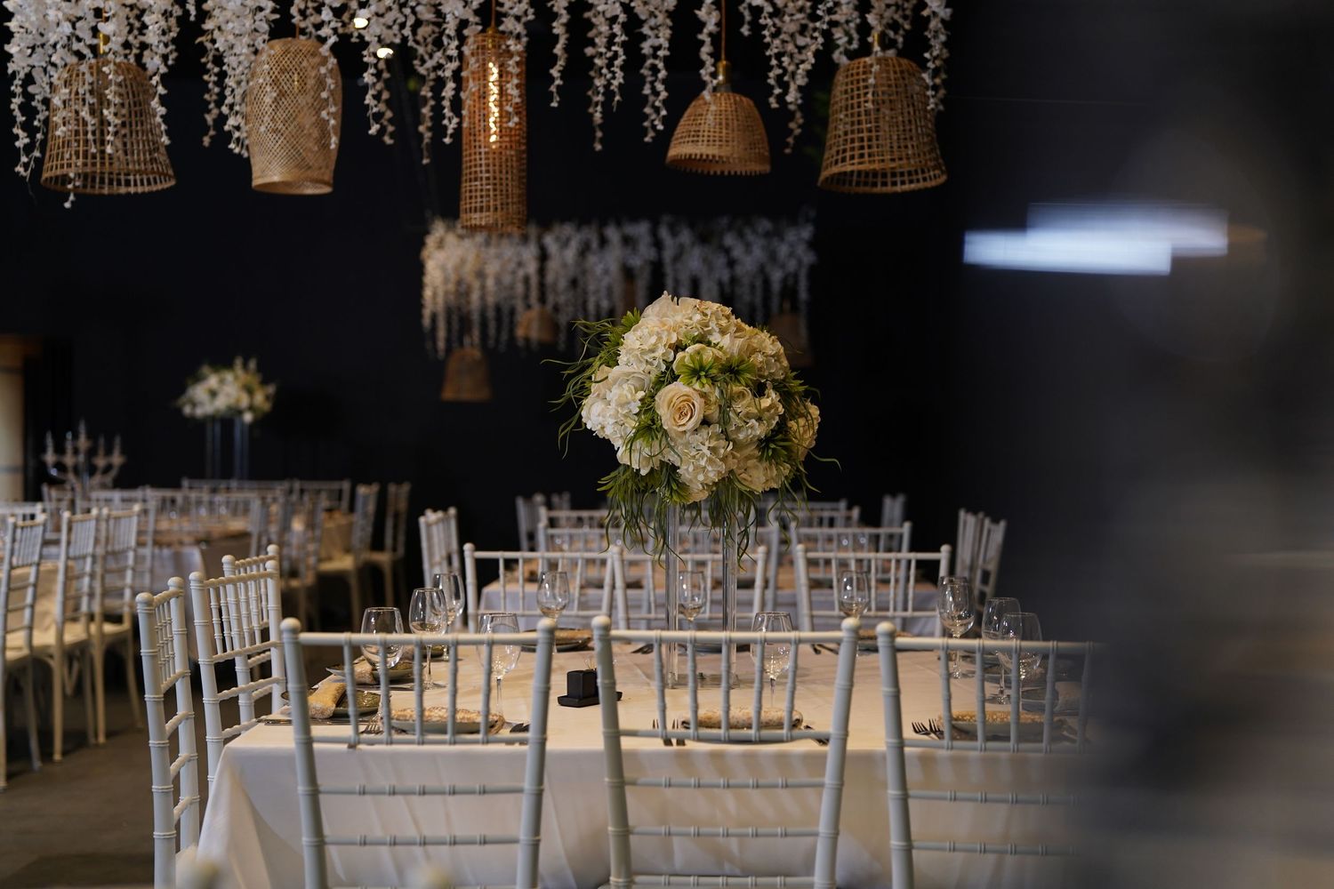 White chairs arranged in rows with elegant hanging crystal decorations and floral arrangements.