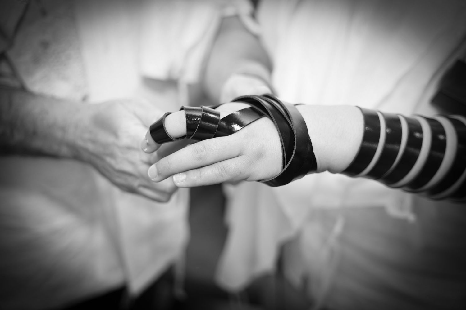 Close-up black and white image showing hands during a religious ceremony or ritual.