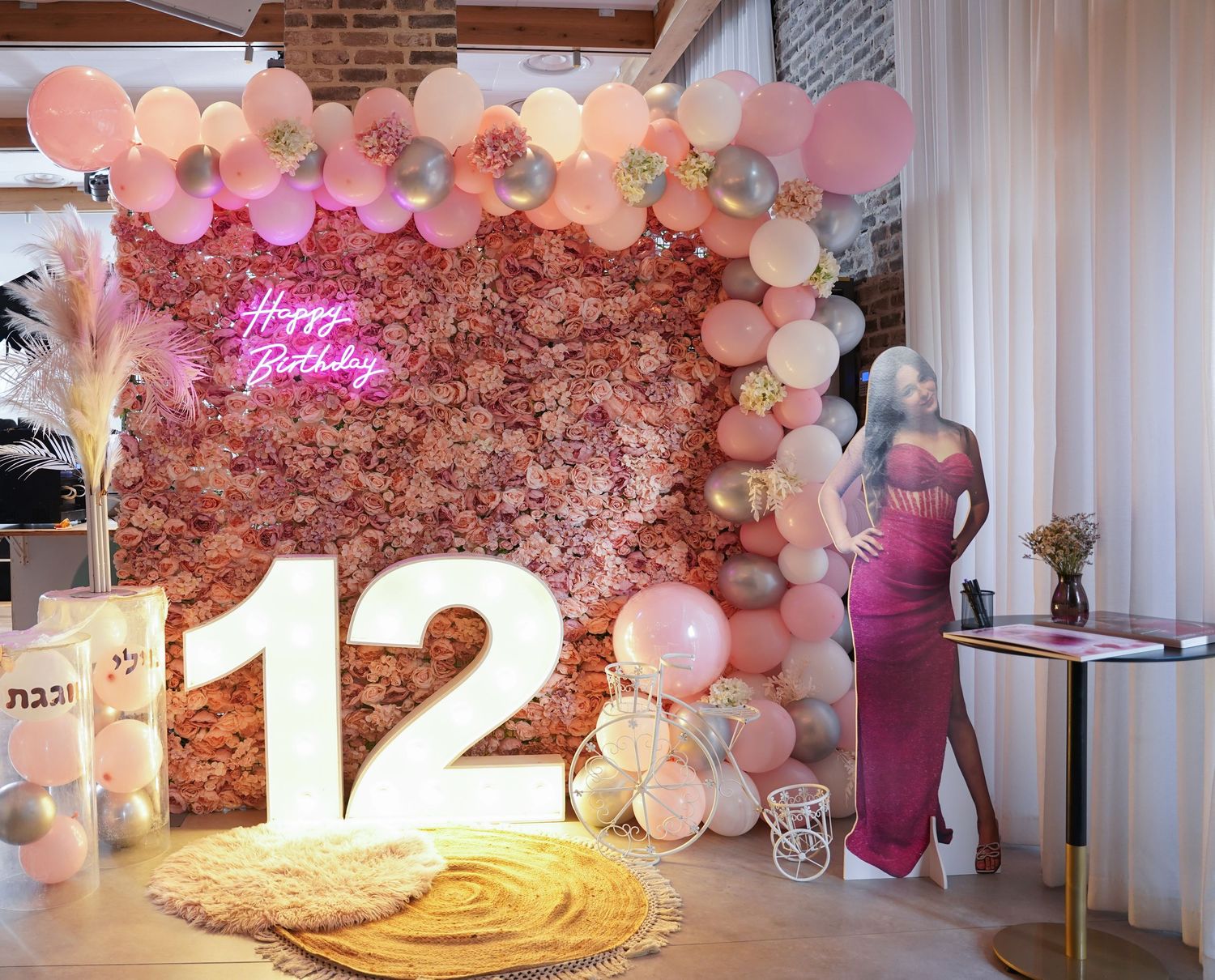 Birthday party setup with large '12' numbers, balloon arch, and floral backdrop.