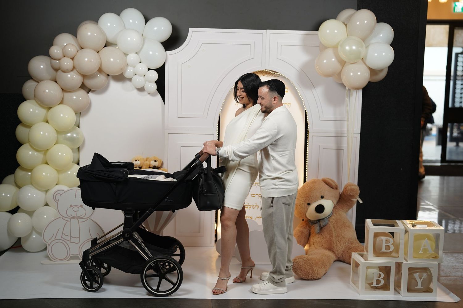 Professional photography studio setup with balloon garland and baby-themed decorative elements.
