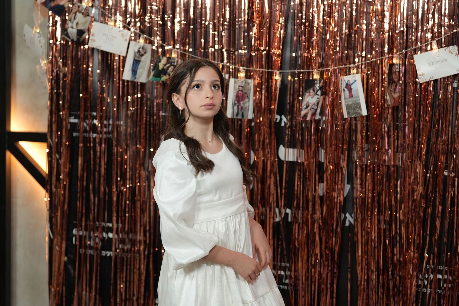Person in white dress poses against shimmering copper-colored tinsel backdrop in multiple candid shots.