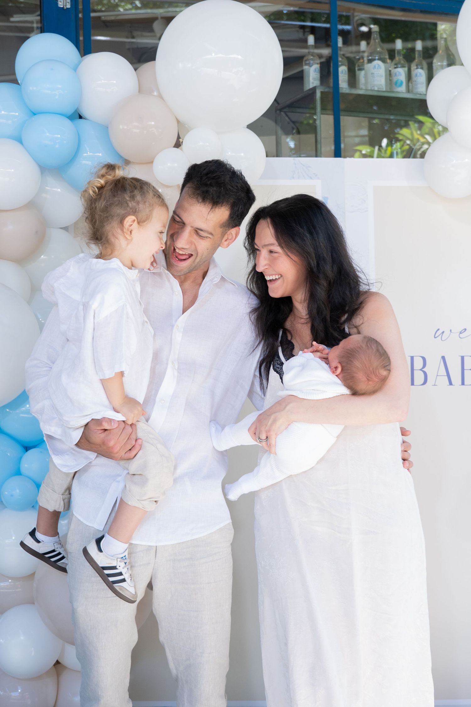 Family celebration with white and blue balloon decorations and coordinated white outfits.