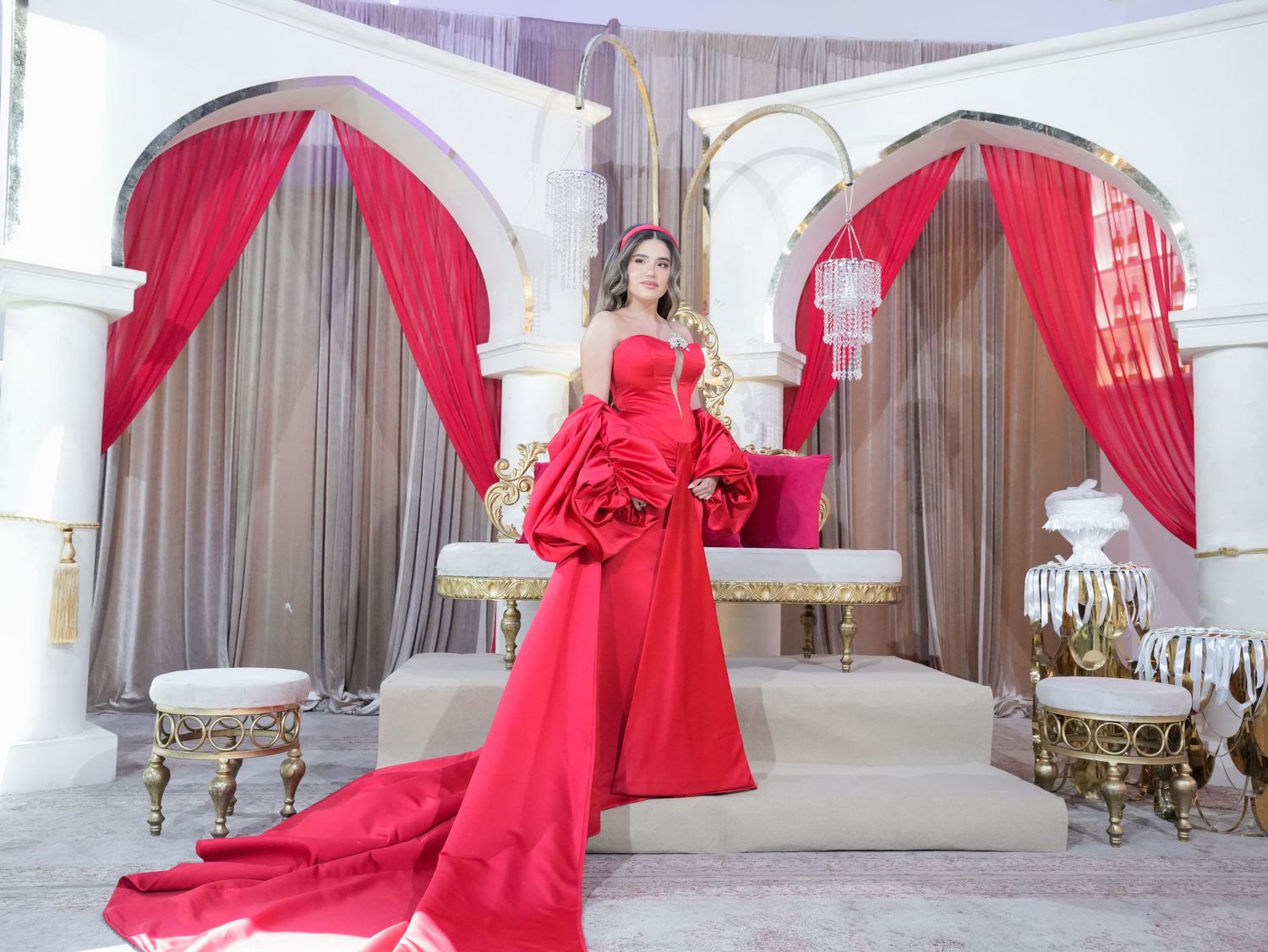 Wedding venue featuring red fabric installations and white architectural columns creating a dramatic atmosphere.