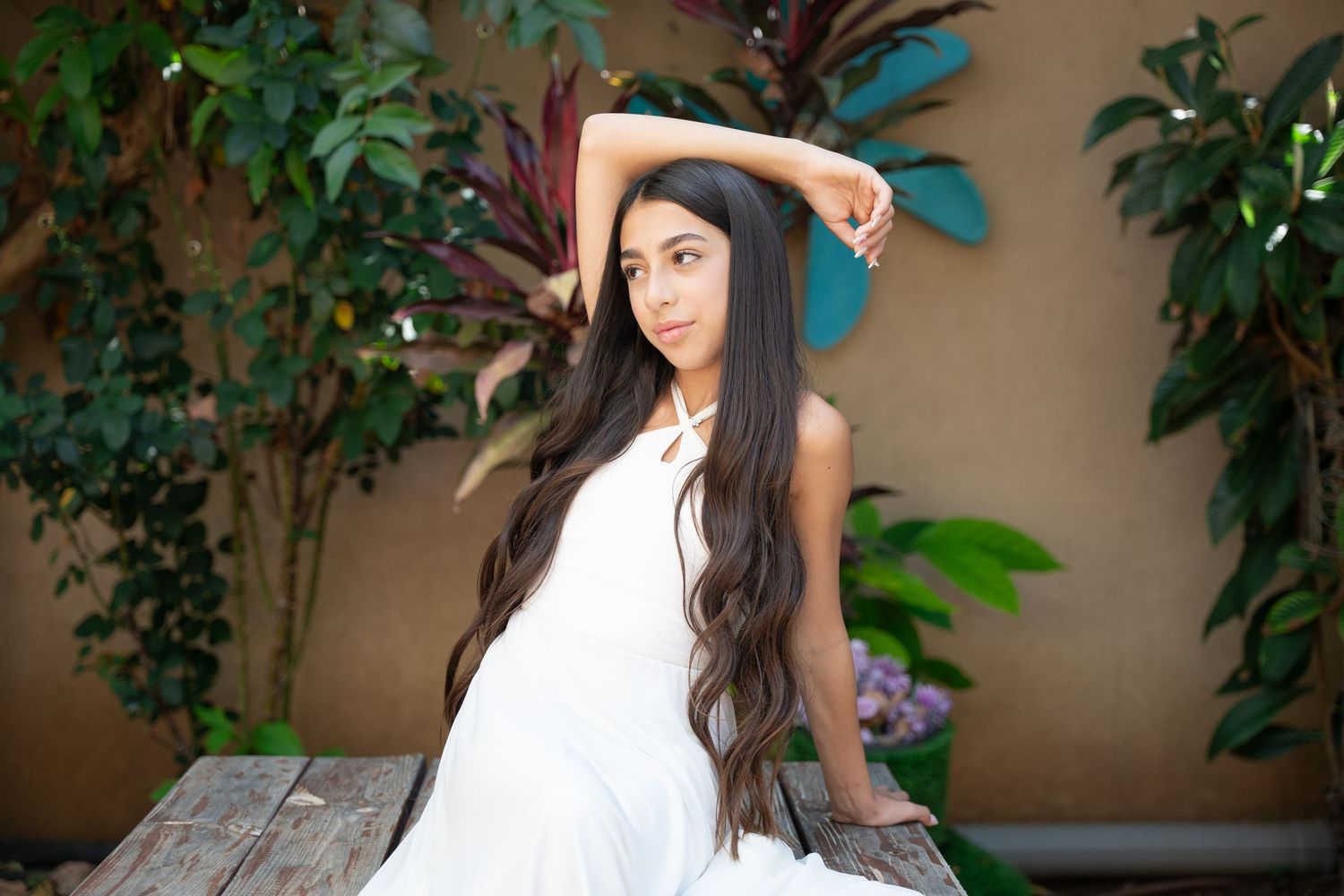 Artistic outdoor photoshoot among lush green plants with soft natural lighting.