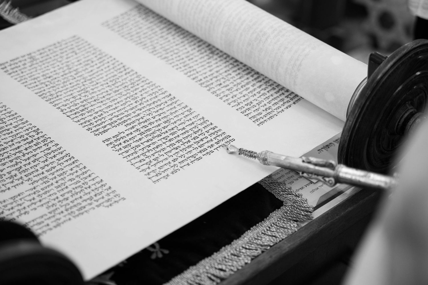 Black and white close-up image of an open book with text visible on its pages.