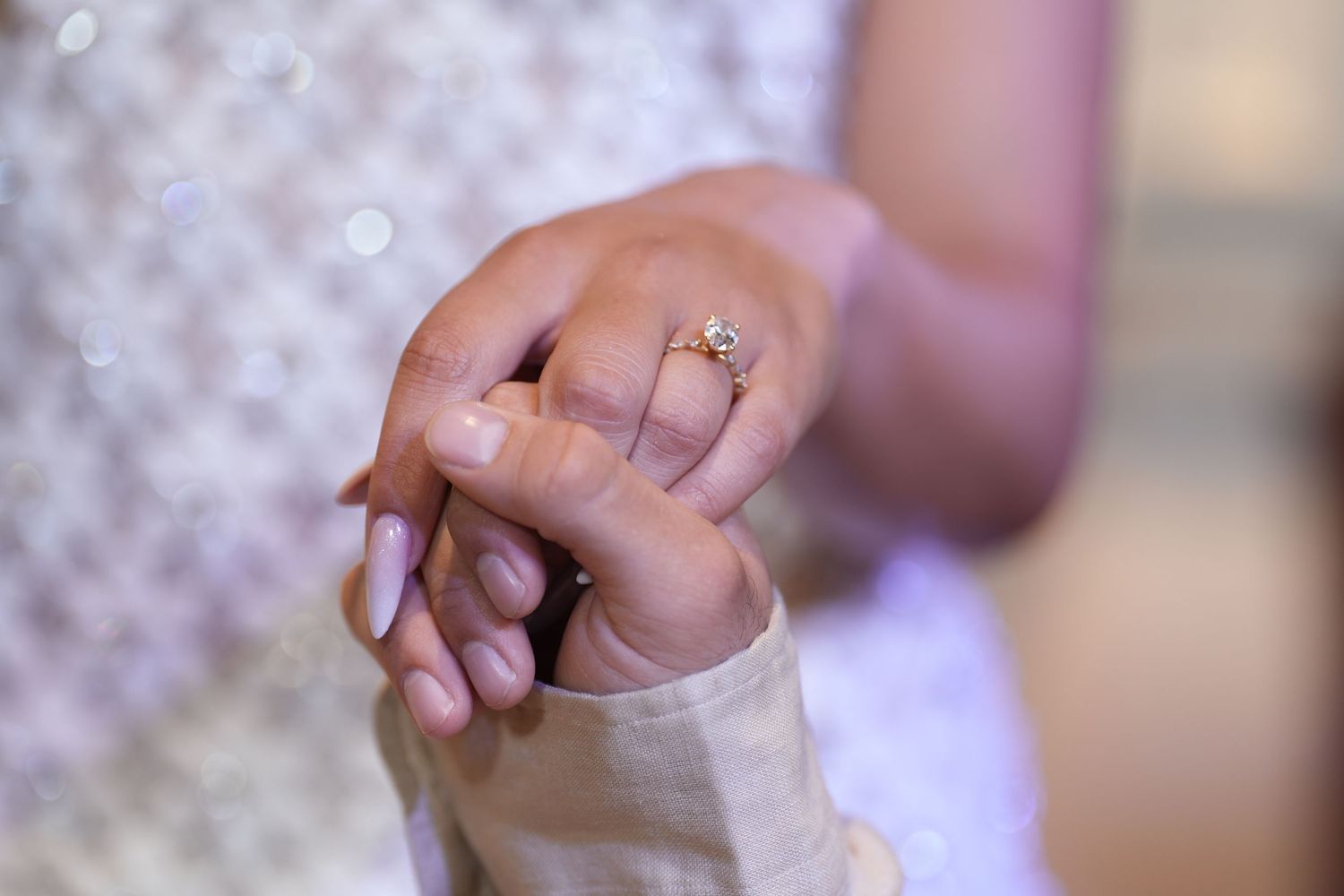 Close-up of two hands holding, one adorned with a delicate diamond engagement ring, symbolizing love and commitment.