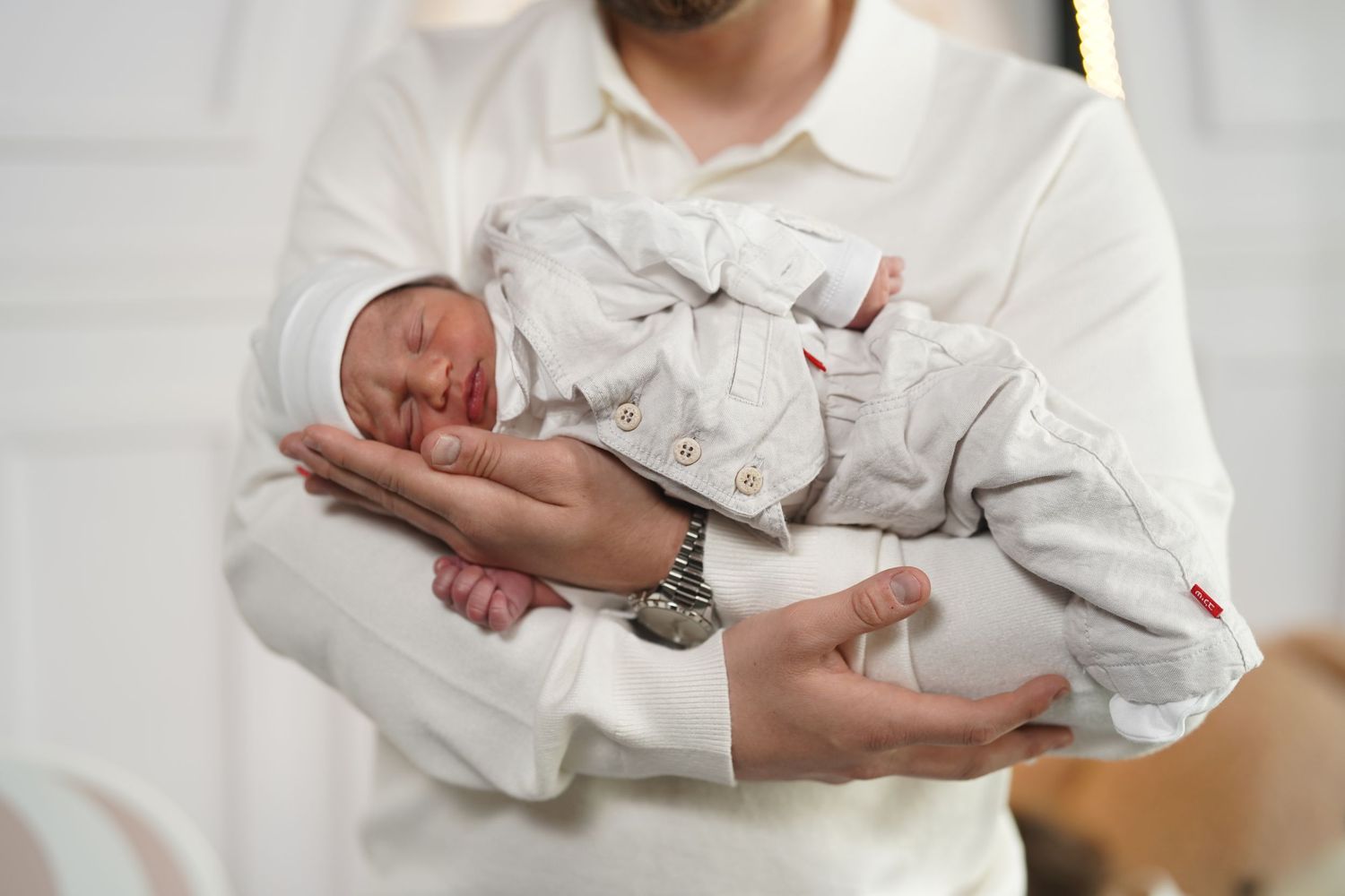 Tender moment captured during a newborn photography session with white and neutral tones.