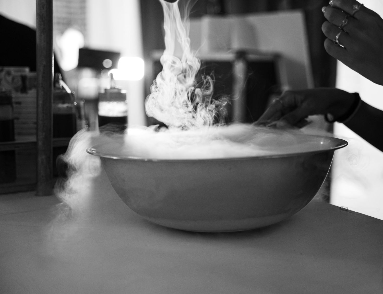 Black and white photo of a smoking bowl with dry ice effect creating dramatic fog.