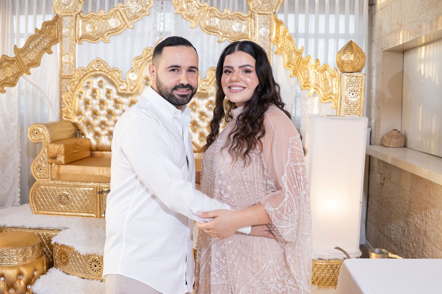 Couple sharing affectionate moment against elegant gold and white decor setting.