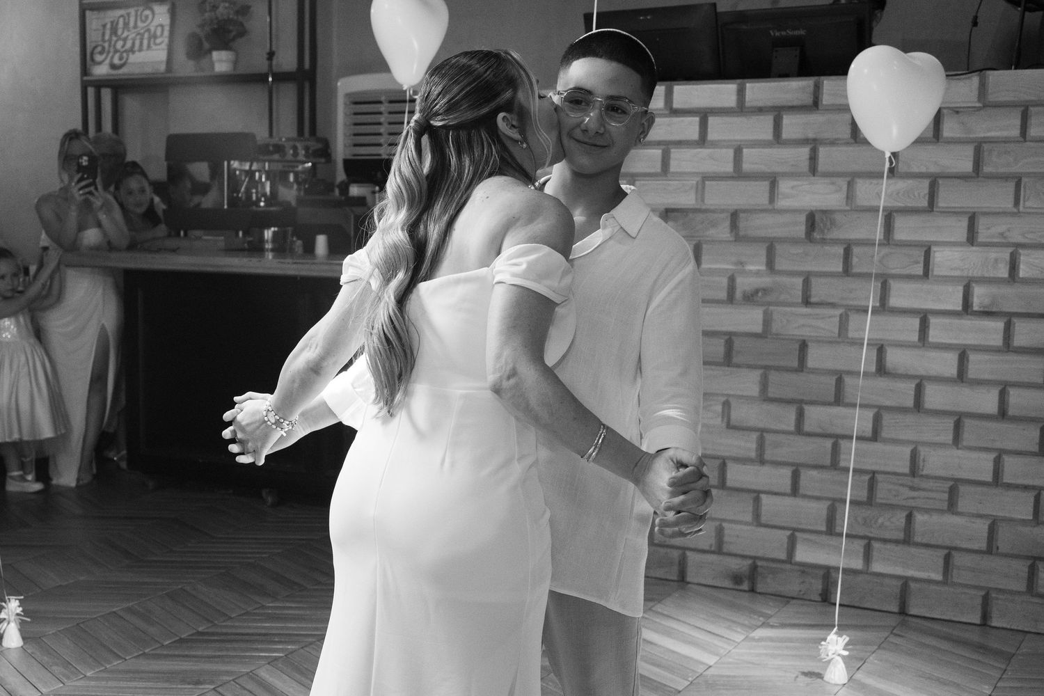 White balloons and brick walls create an elegant backdrop for wedding photography.