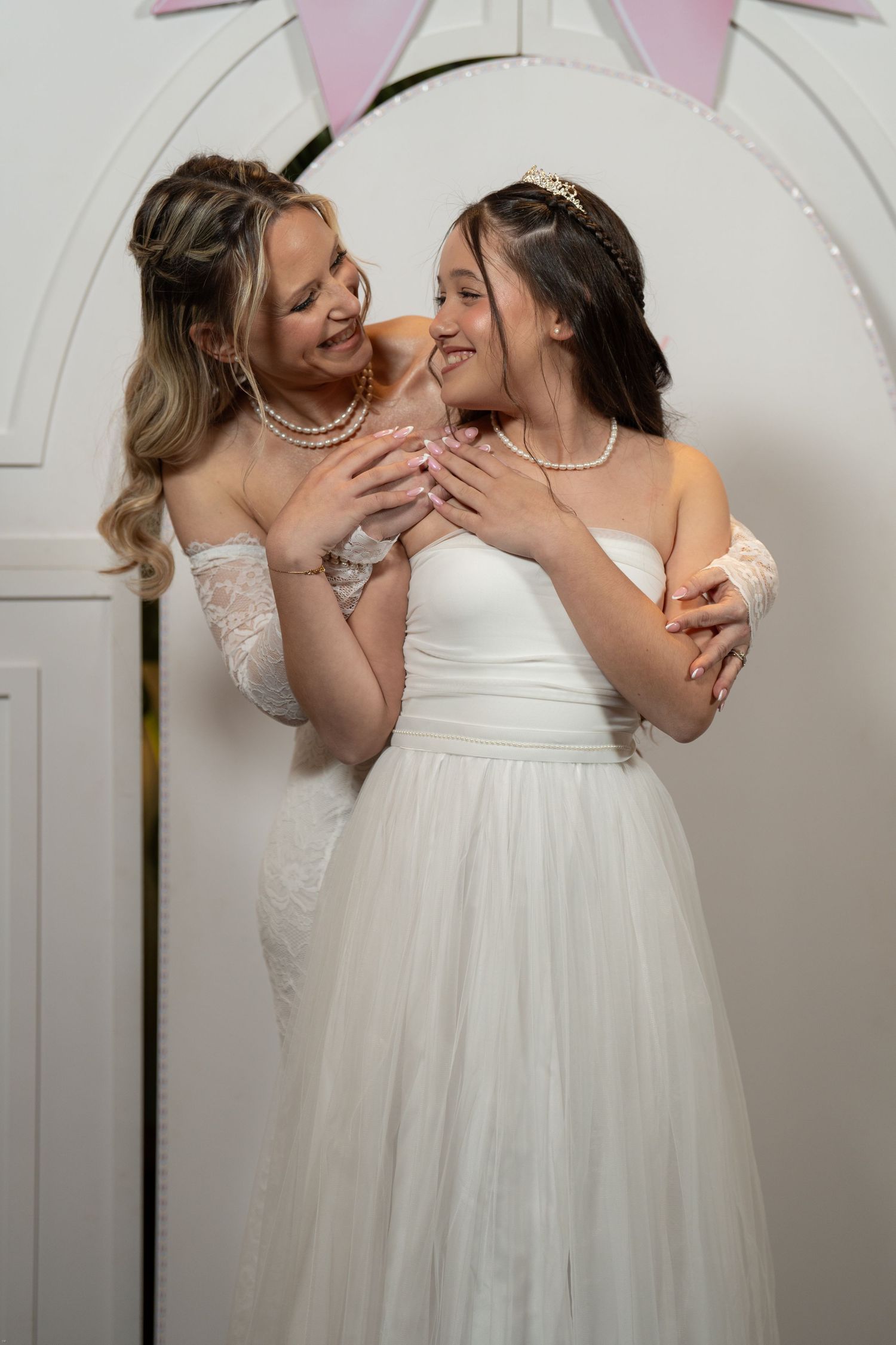 Two people in white wedding dresses share intimate moments in a series of joyful poses against a white backdrop.