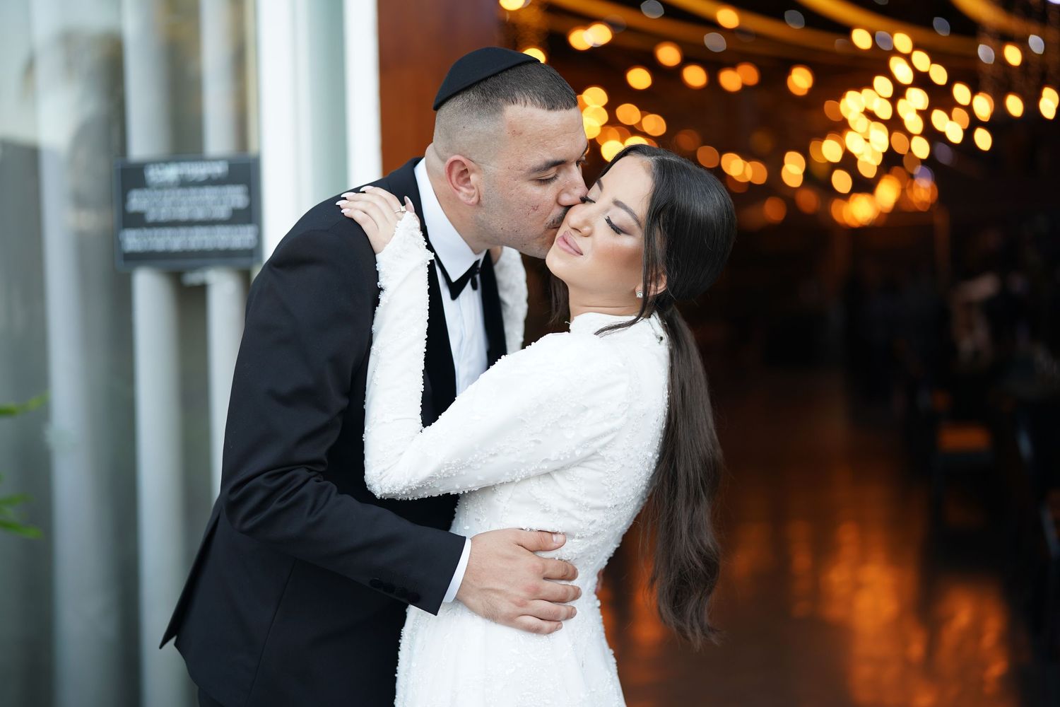 A romantic dance between a couple in formal wedding attire illuminated by warm overhead lighting.