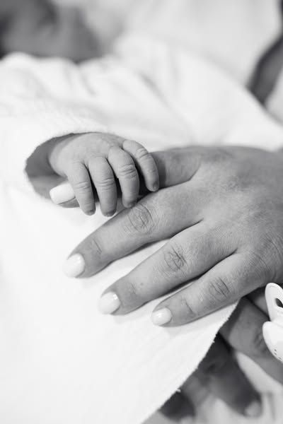 Close-up black and white photo of baby's hand holding parent's finger.