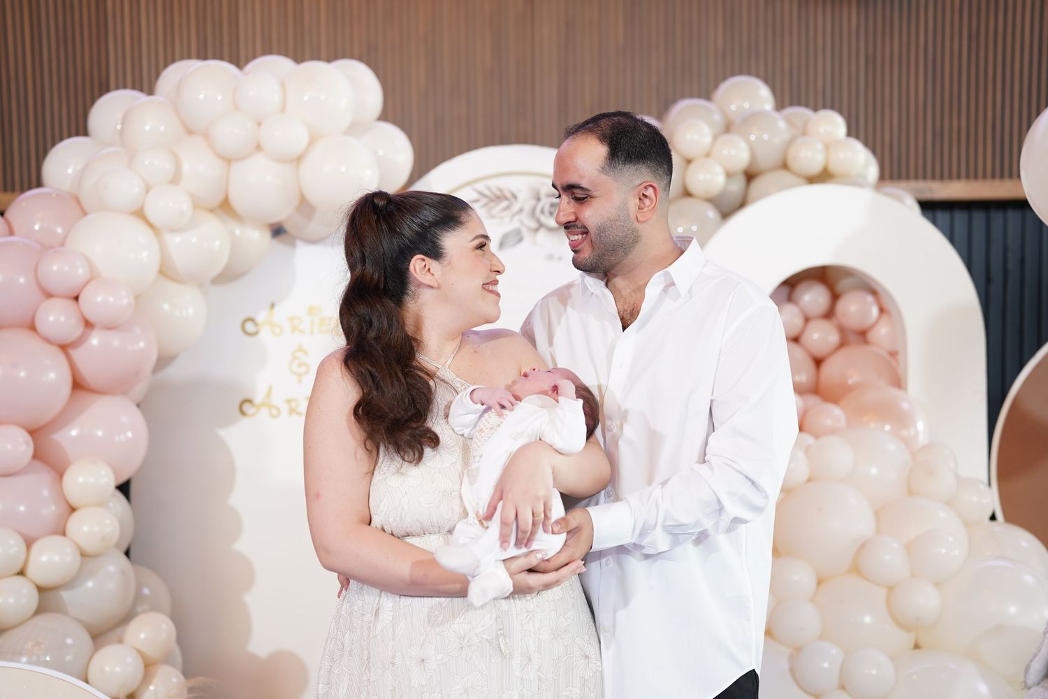 Romantic couple poses against elegant balloon wall backdrop in wedding photography session.