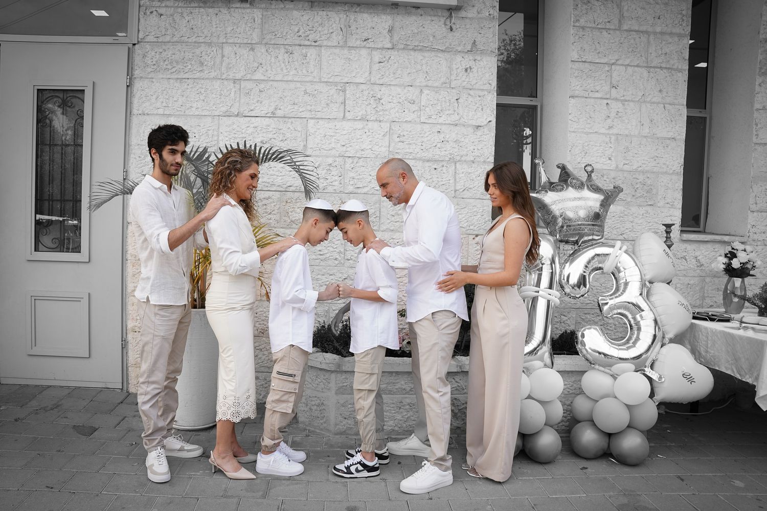Black and white photo of people gathered along a wall with balloons and decorations.