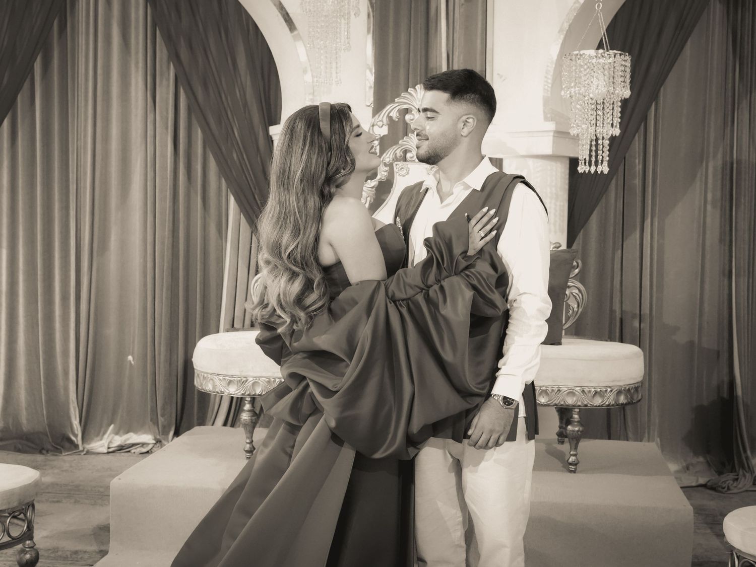 Elegant red gown photoshoot in a luxurious venue with dramatic curtains and lighting.