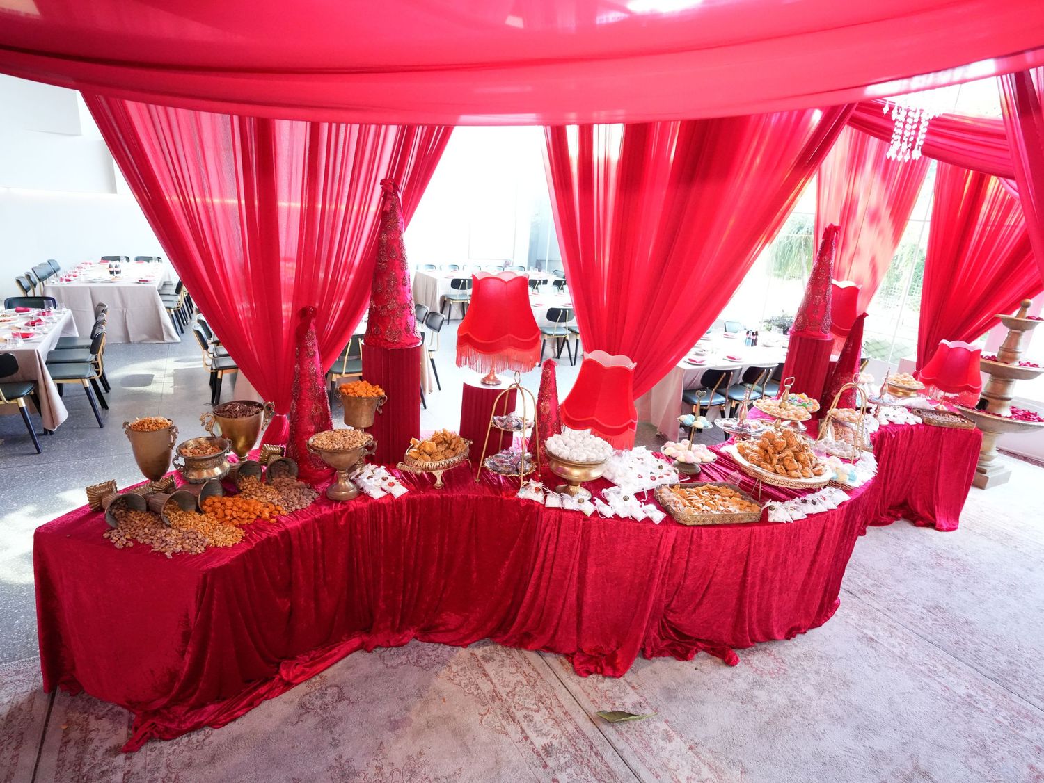 Wedding buffet table decorated with flowing red fabric drapes and elegant food displays.