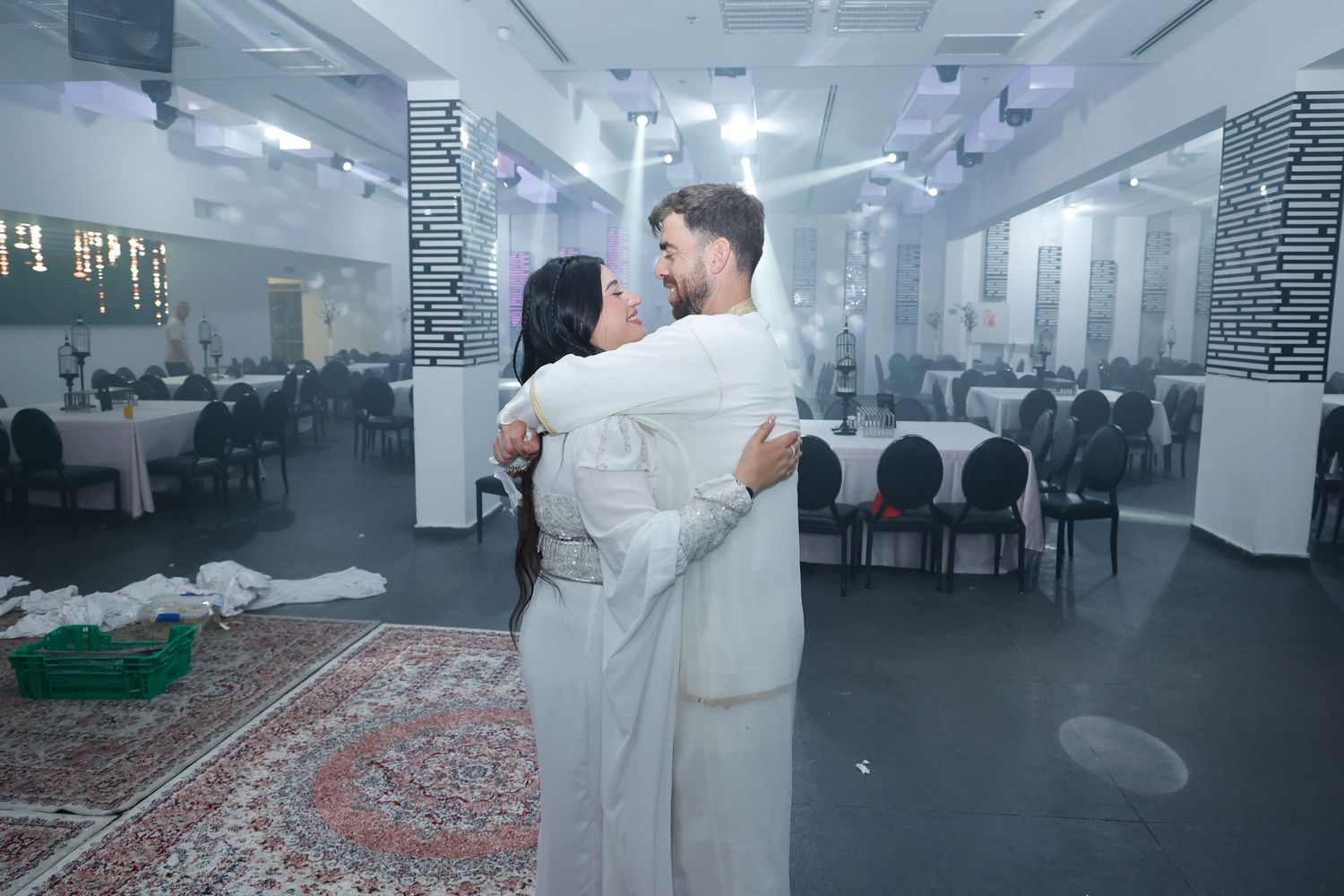 Modern wedding reception space with white decor and dramatic lighting creating an elegant atmosphere.